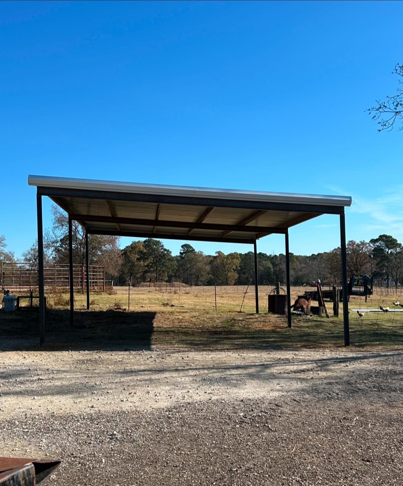 A metal shed in a rural field on a sunny day with blue sky overhead.