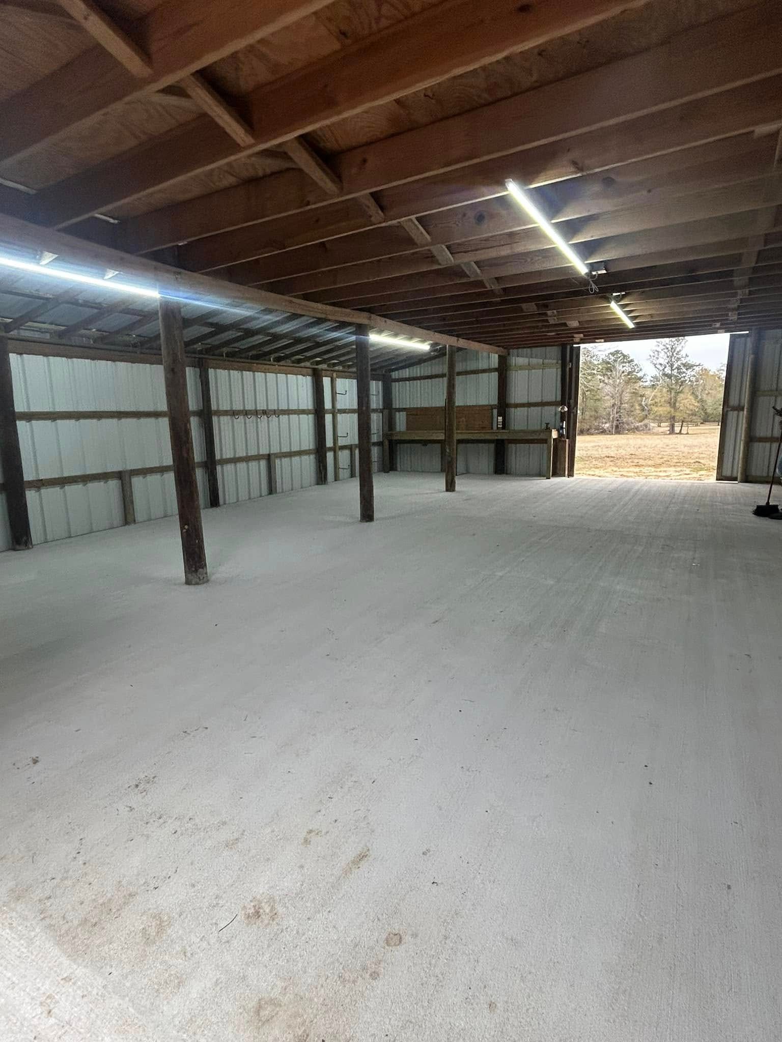 Empty, dusty interior of a shed with wooden beams and open doorway.