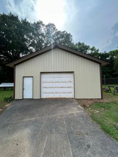 Tan garage with a white door and garage door on a concrete driveway.
