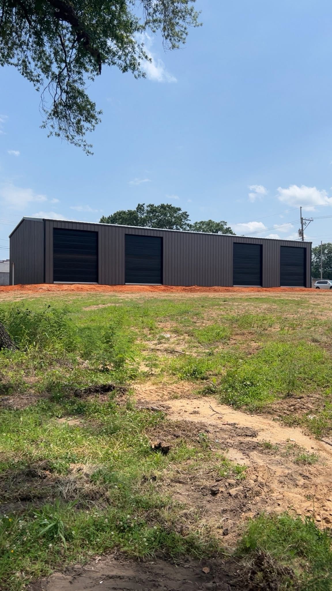 Brown storage units with black doors in a field on a sunny day.