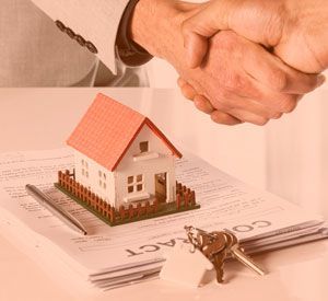 a man is shaking hands with a model house on top of a contract .