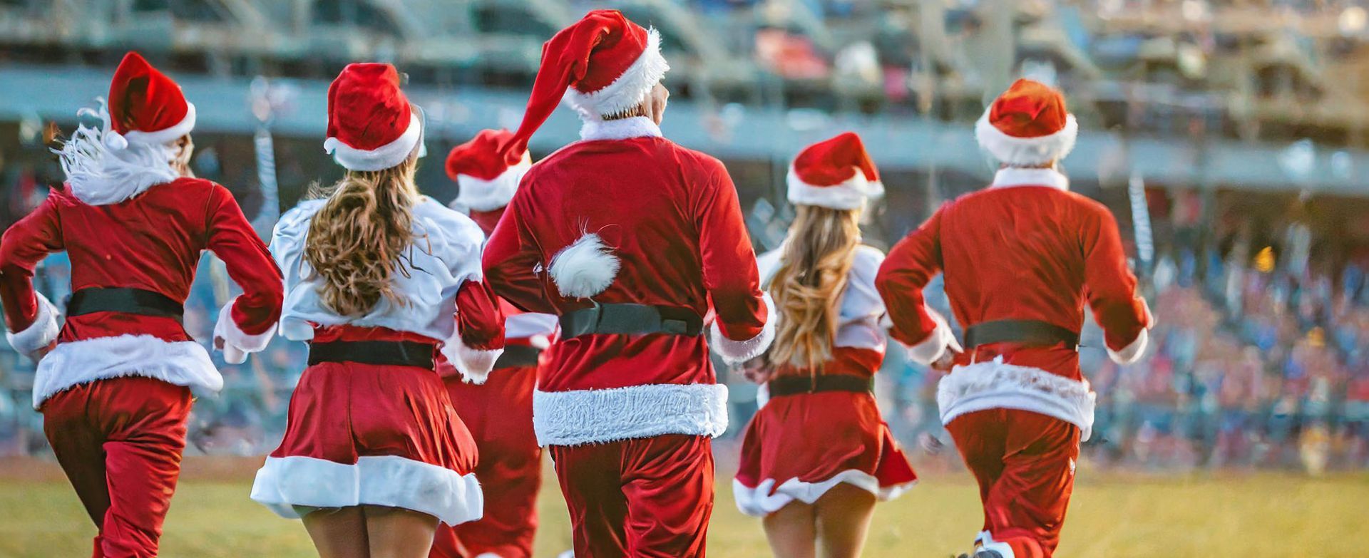 a group of people dressed as santa claus are running on a field for Julias House 