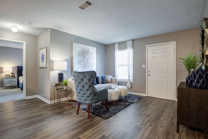 Living room with gray walls, wood floors, furniture, and a white door.