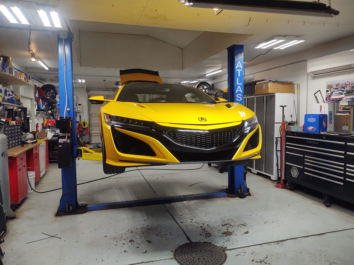 Yellow sports car on a lift in a garage.