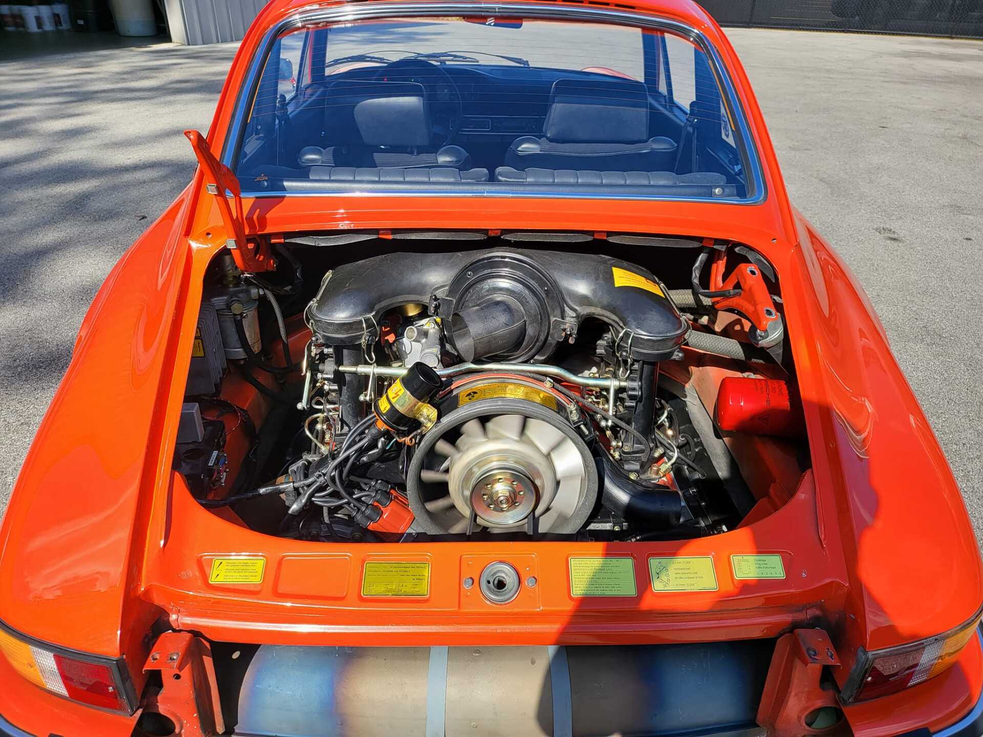 Orange Porsche 911 engine bay, open rear lid, air-cooled engine visible.