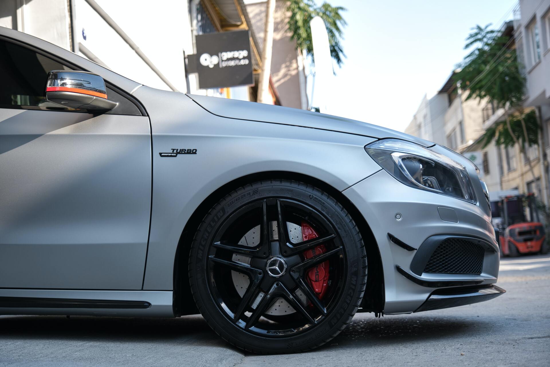 Silver Mercedes-Benz A-Class with black wheels and red brake calipers parked on a street.