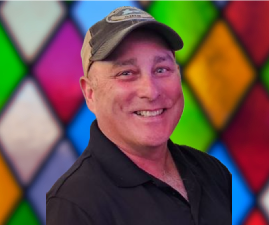 A man is smiling in front of a stained glass window