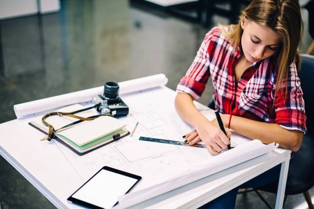 Person working on designing and drafting at a desk with a tablet and notebook.