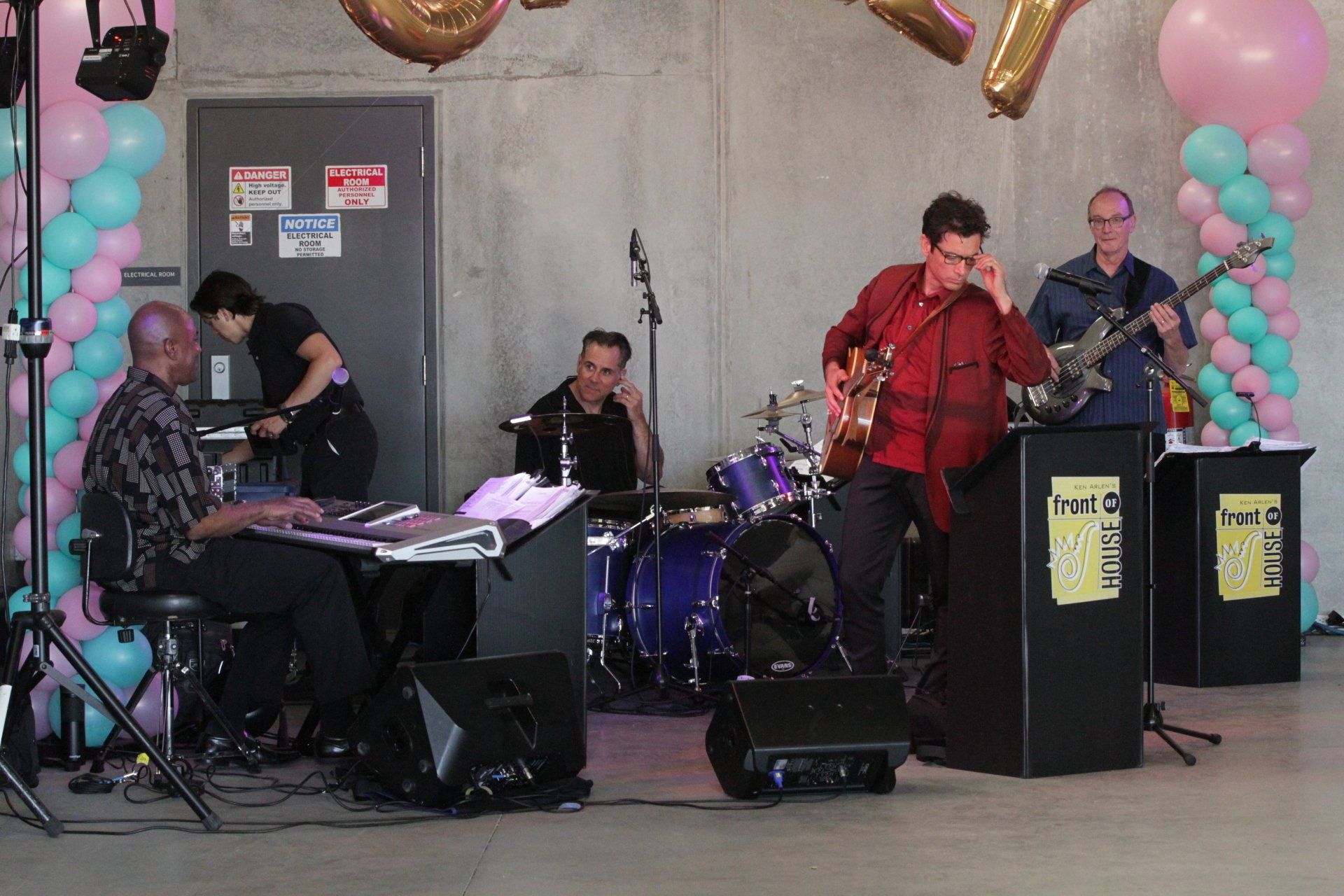 A group of people playing instruments on a stage with balloons in the background