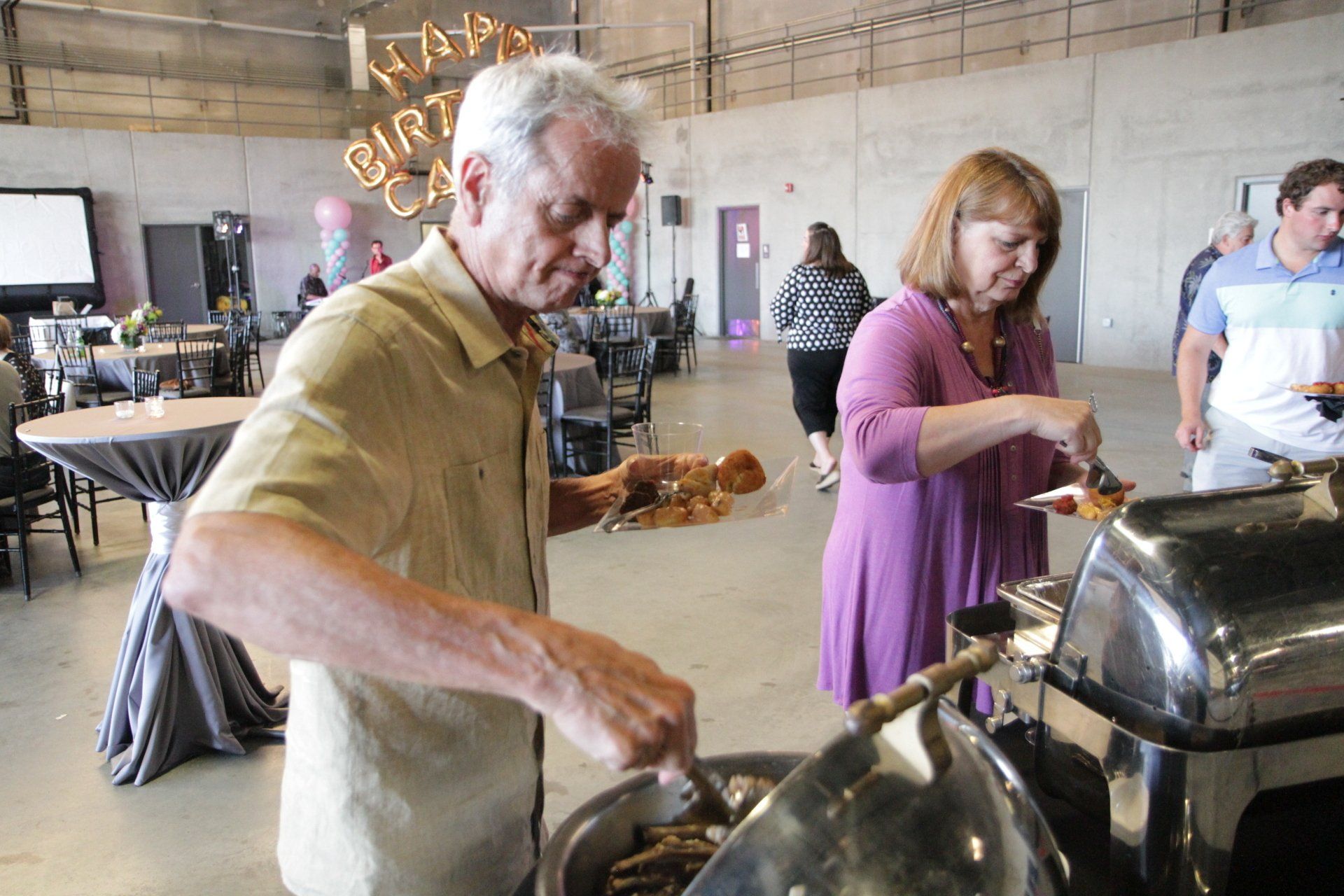 A man and a woman are serving food at a birthday party