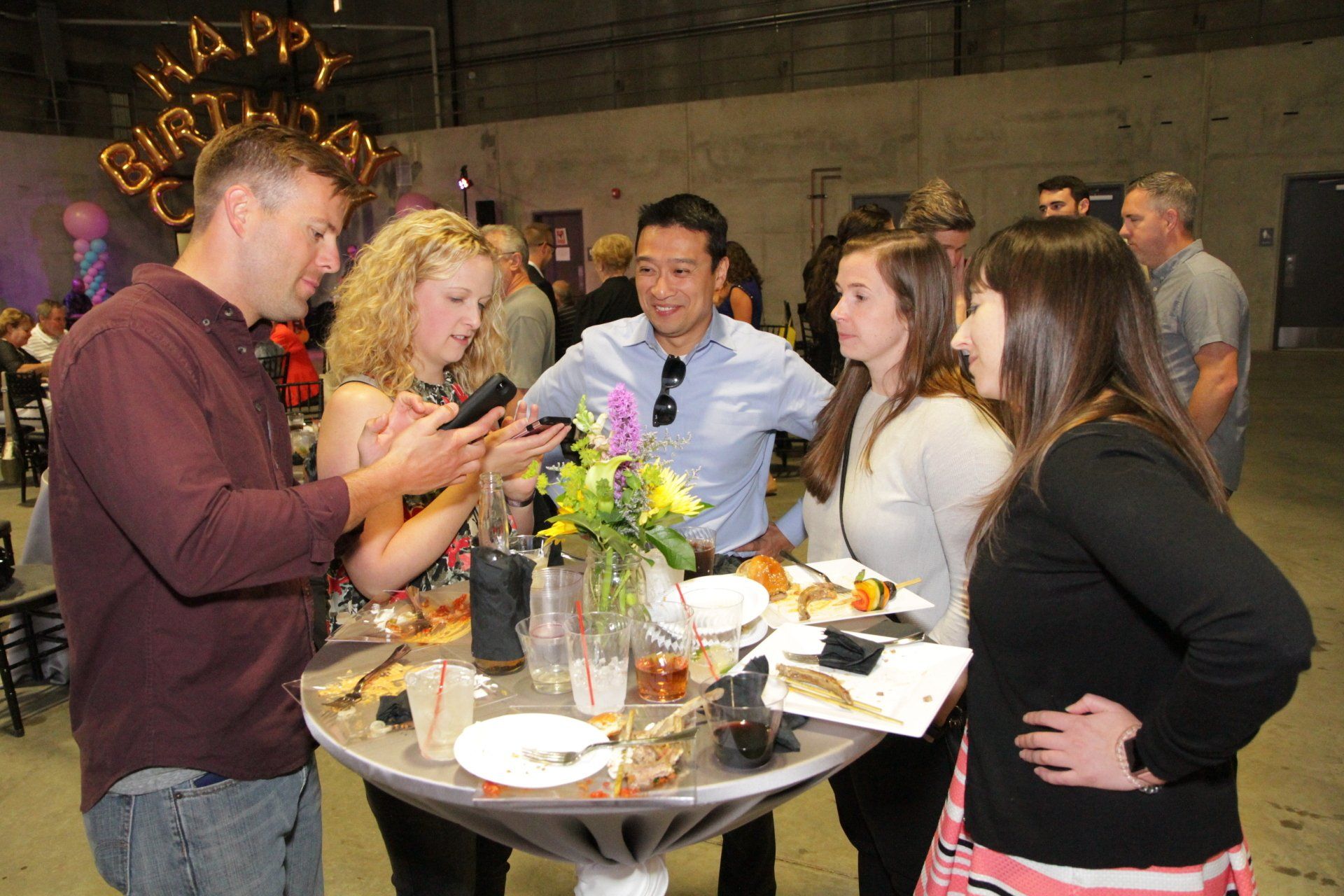 A group of people are standing around a table at a birthday party.