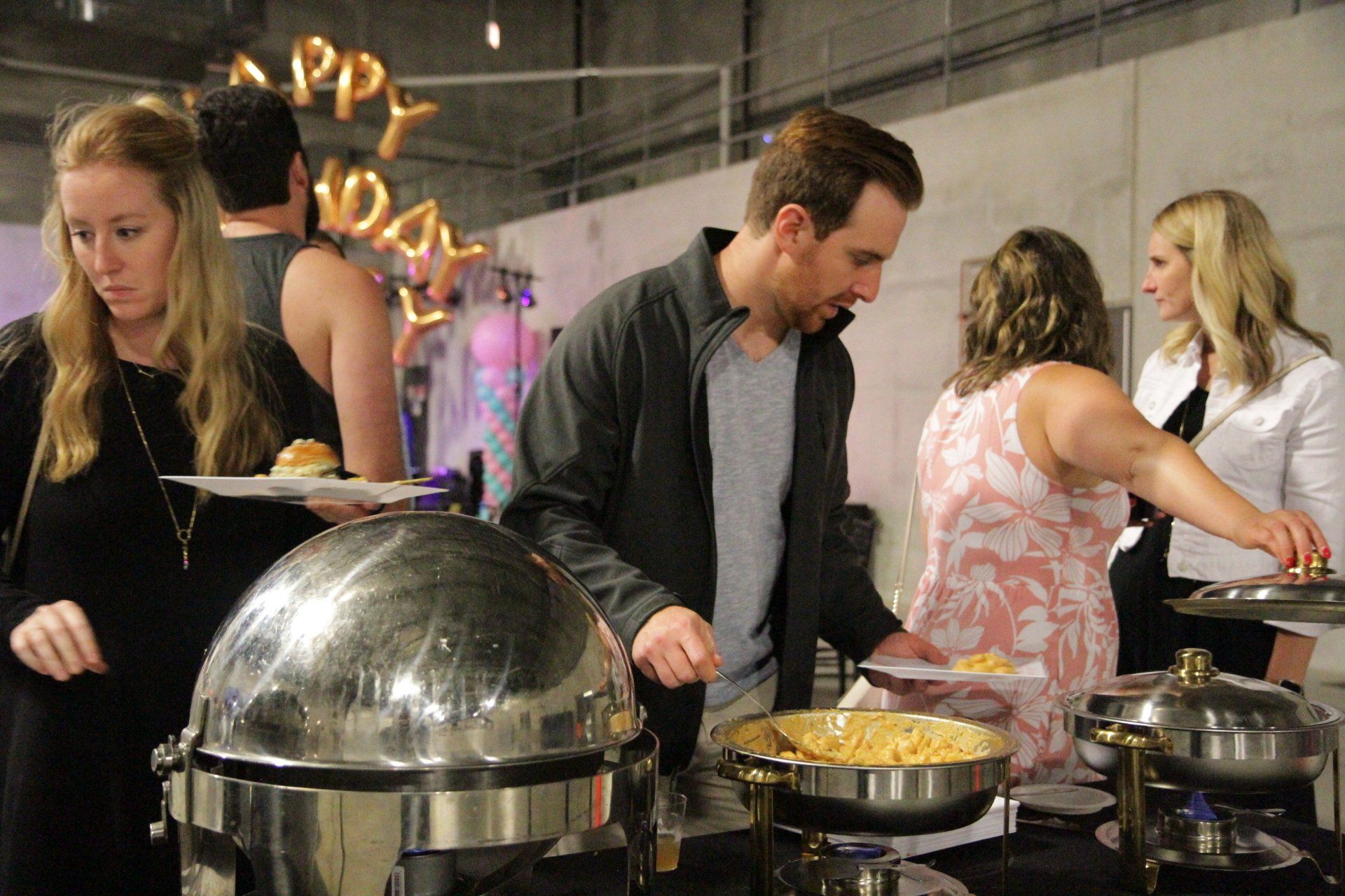 A group of people are standing around a buffet table.