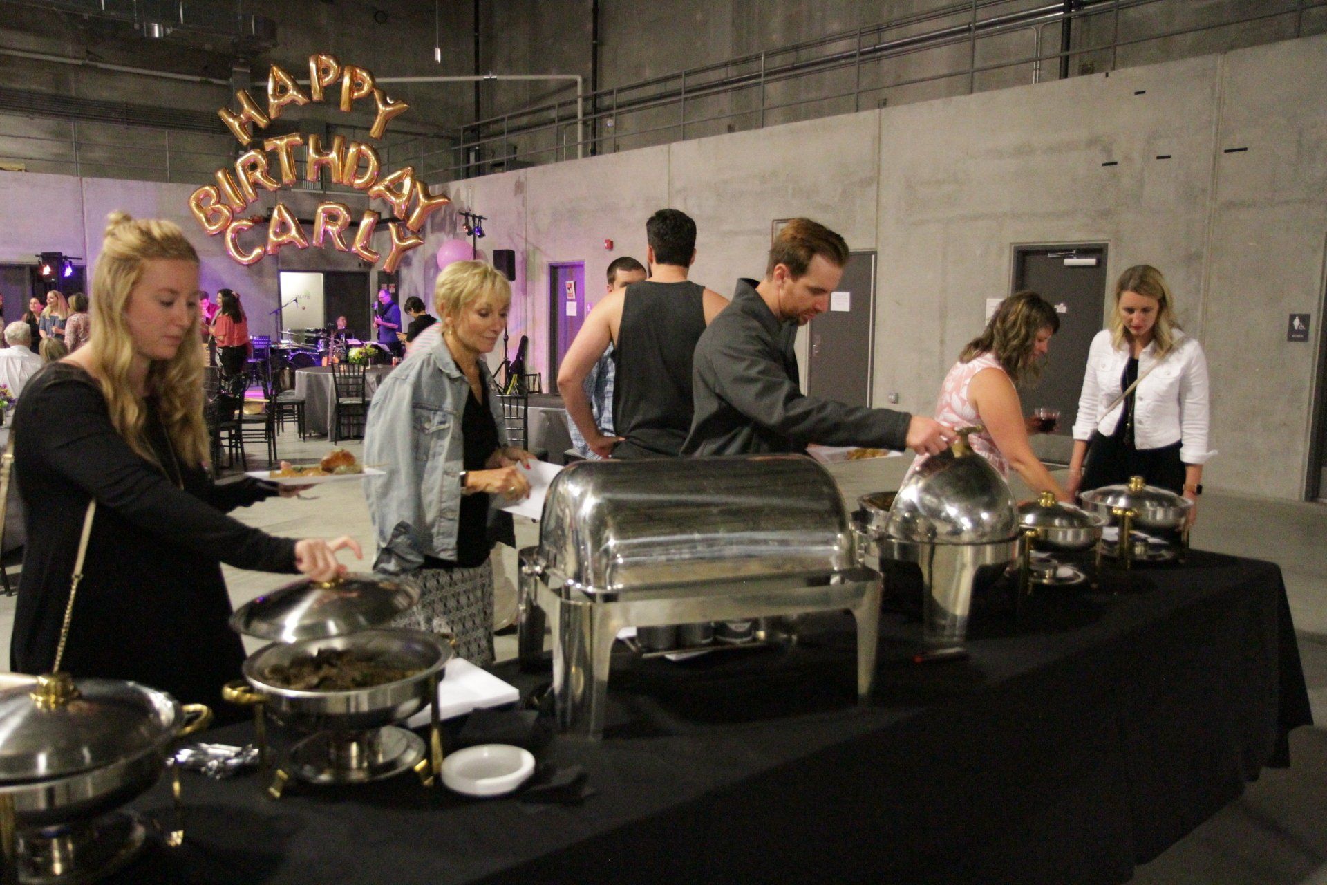 A group of people are standing around a buffet table.