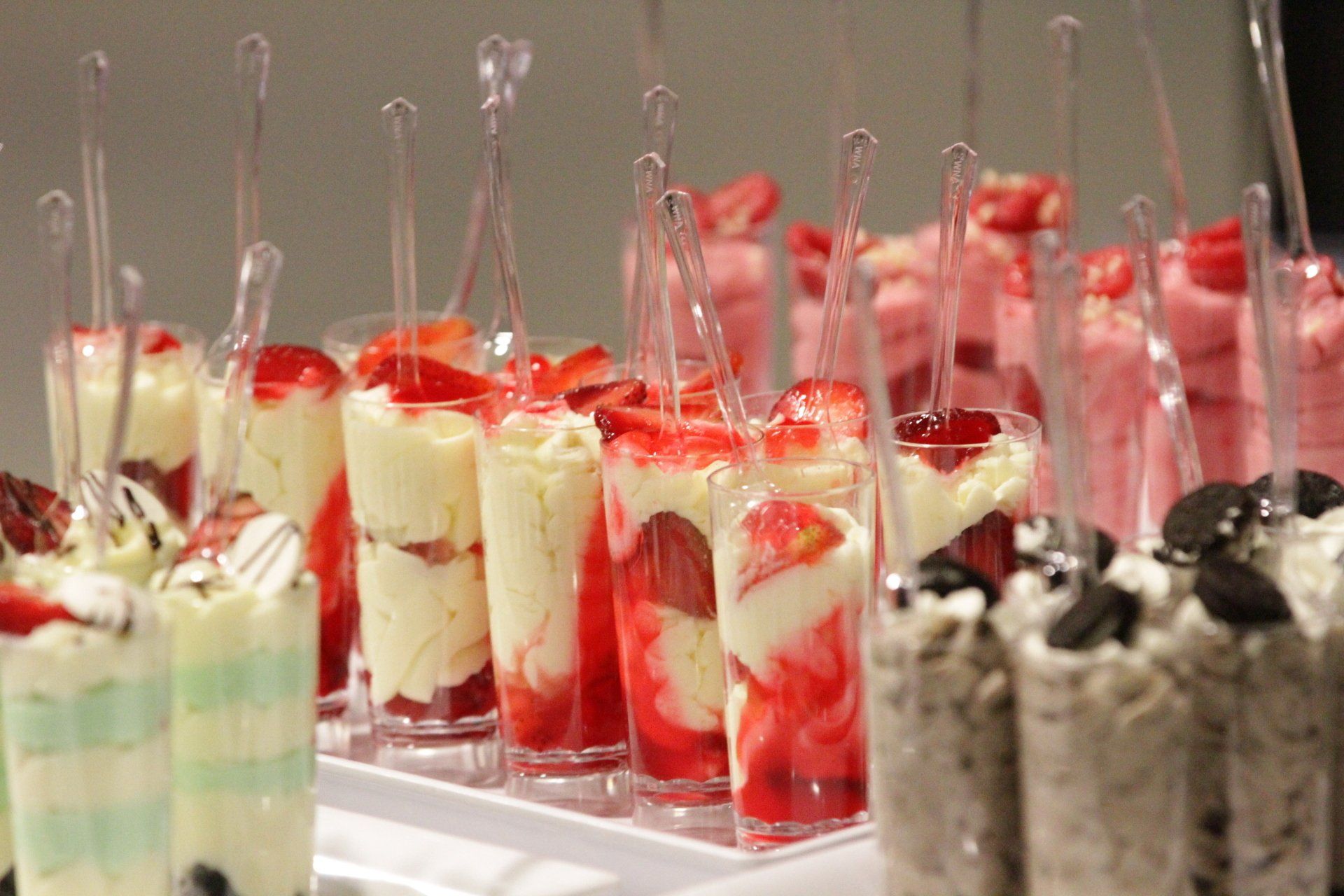 A tray of desserts with strawberries and whipped cream on a table.