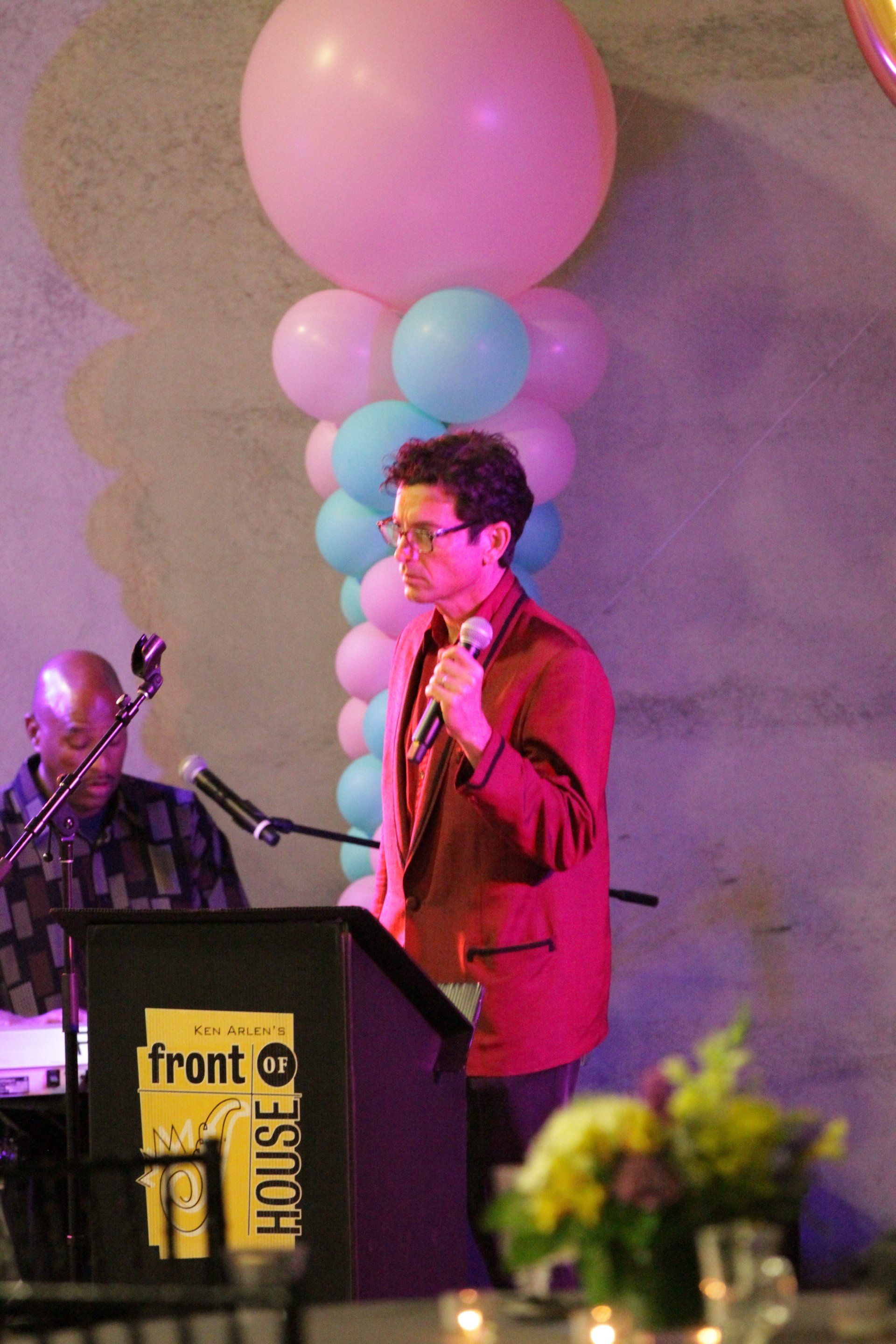 A man is standing at a podium holding a microphone.