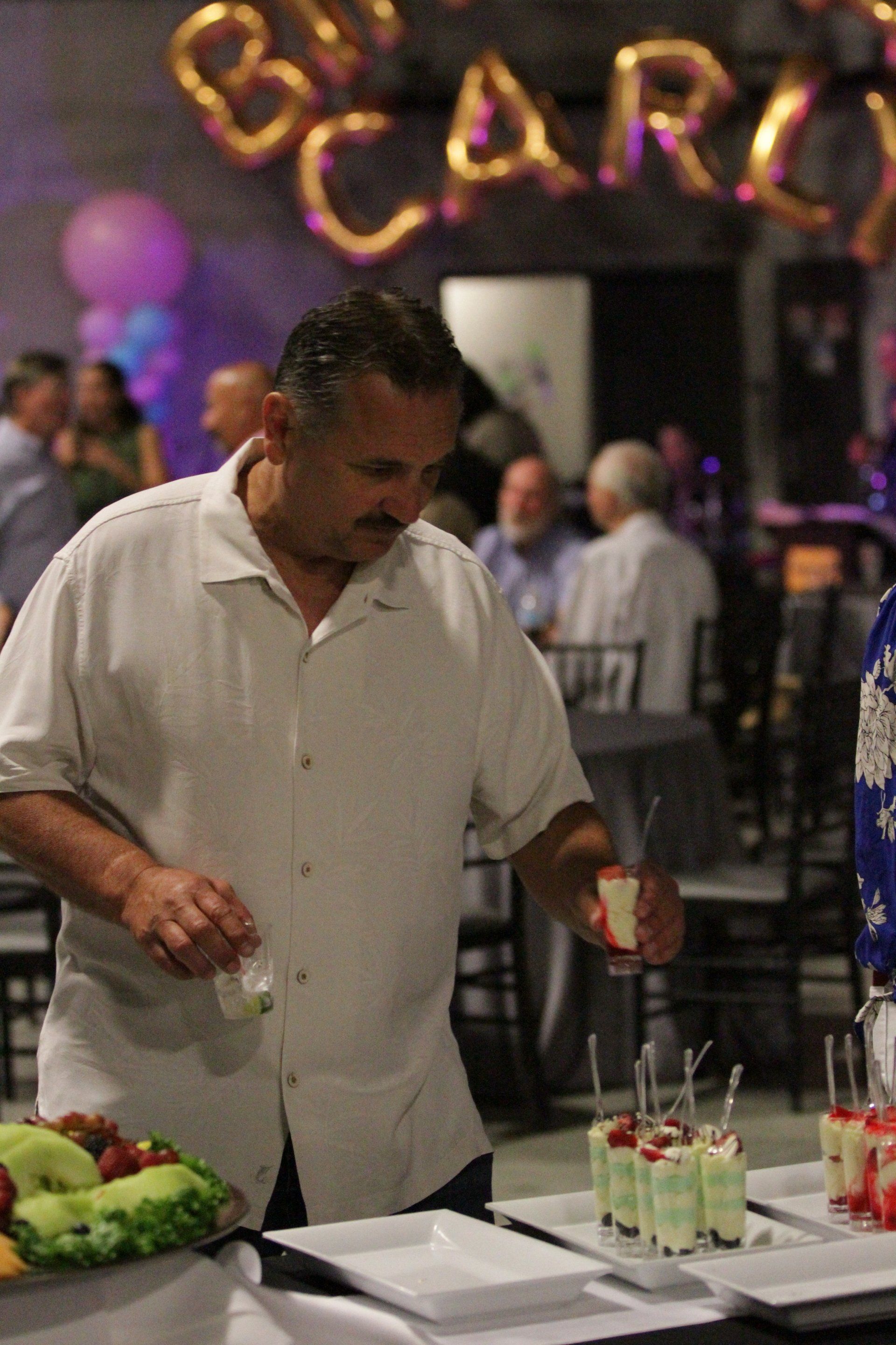 A man in a white shirt is preparing food at a party