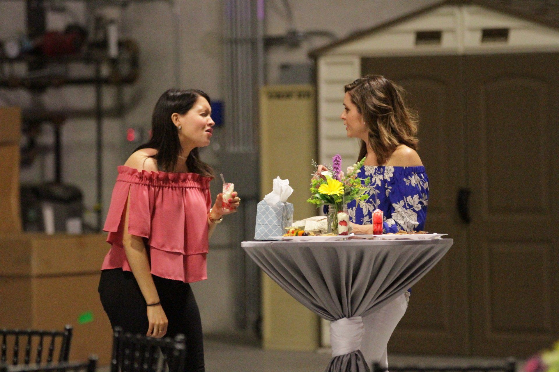 Two women are sitting at a table talking to each other.