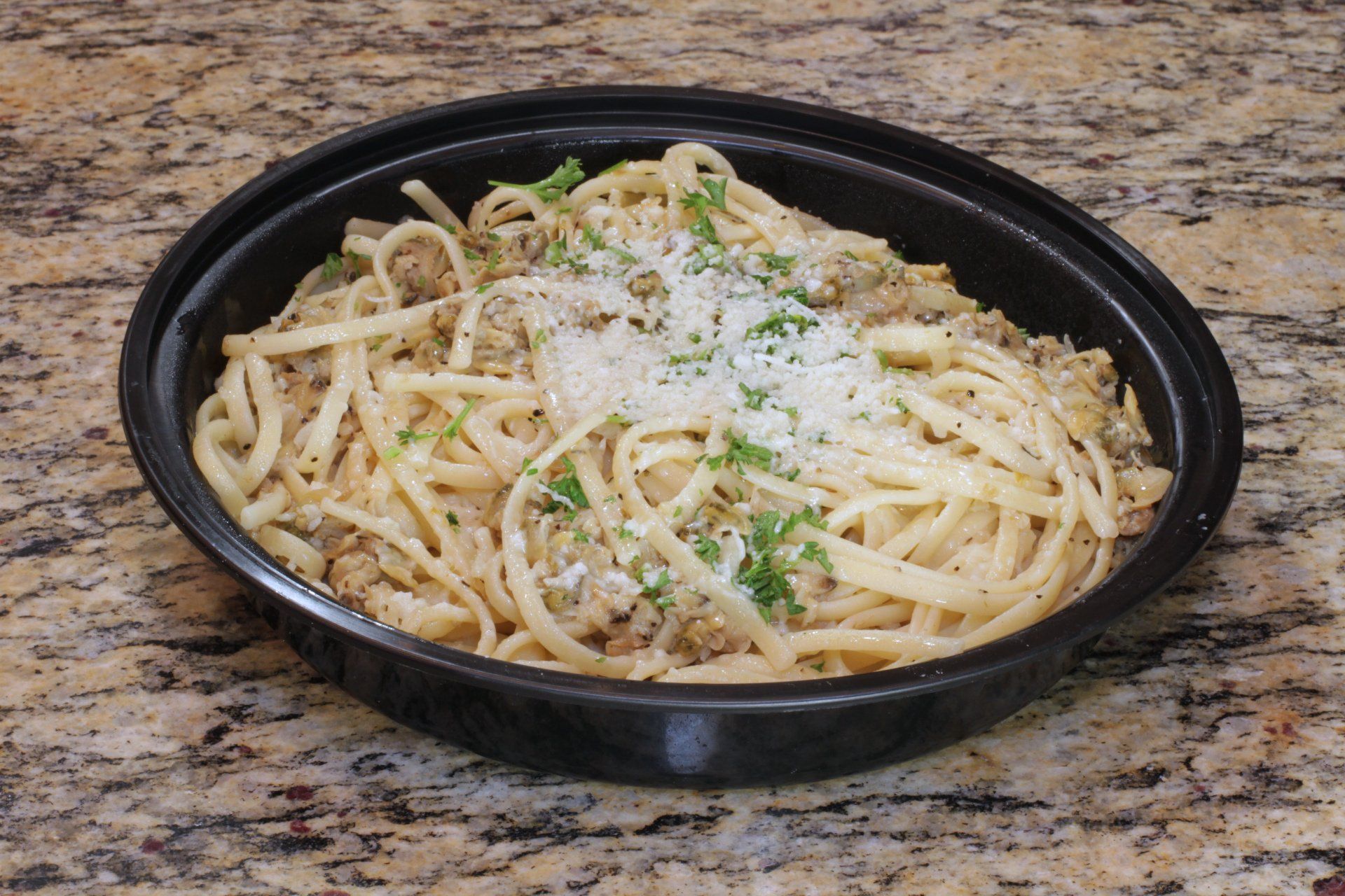 A black bowl filled with noodles and cheese on a table.
