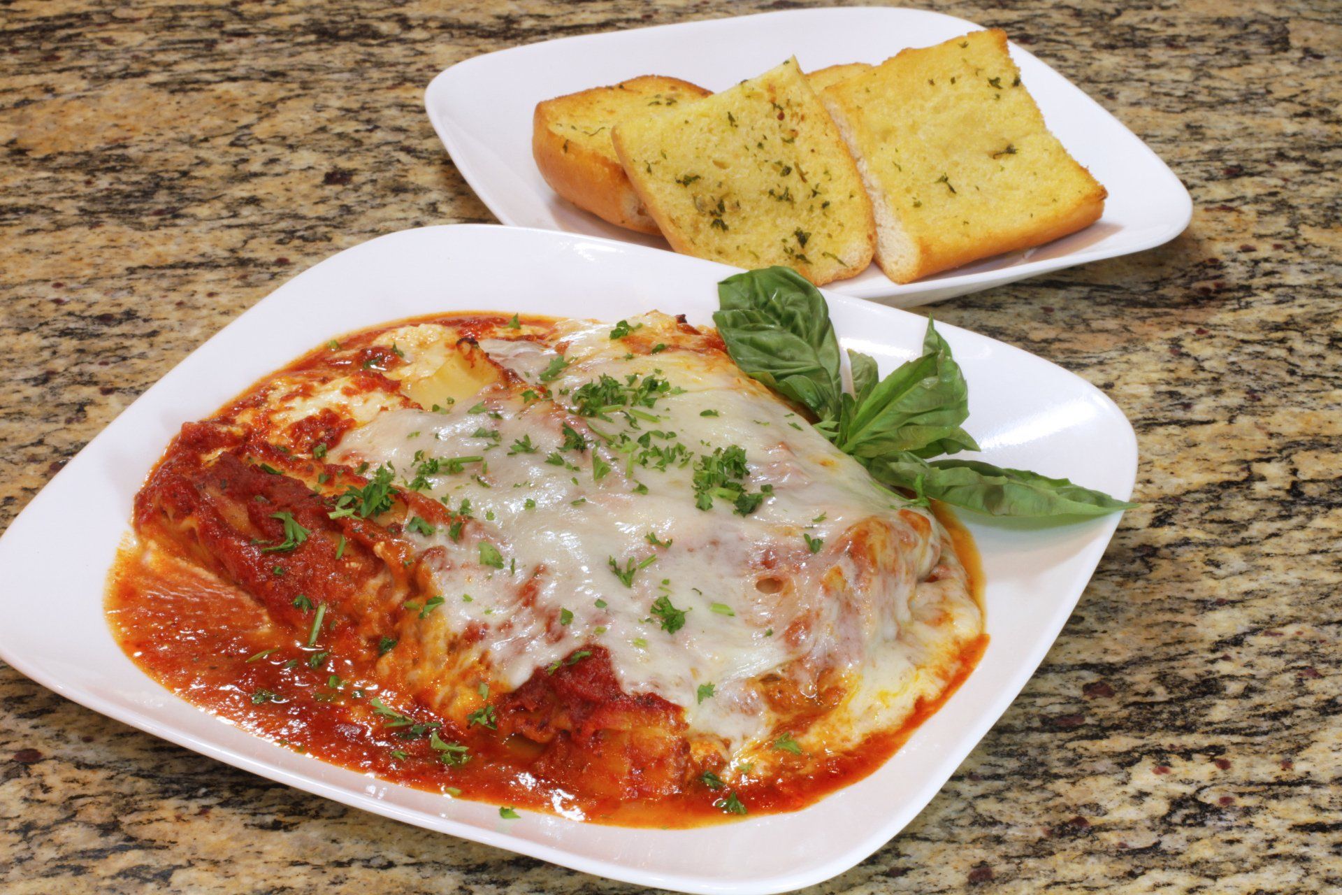 A plate of lasagna and garlic bread on a table.