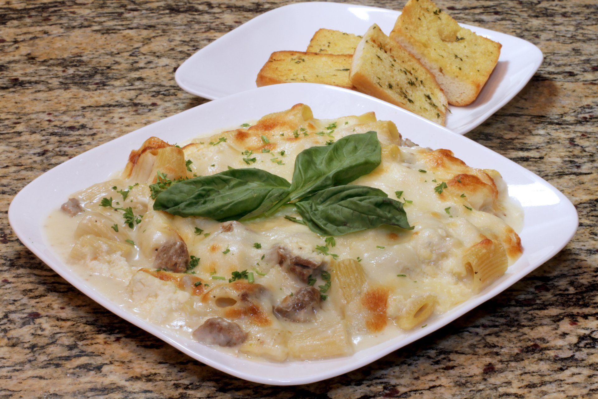 A plate of lasagna with garlic bread on a table.