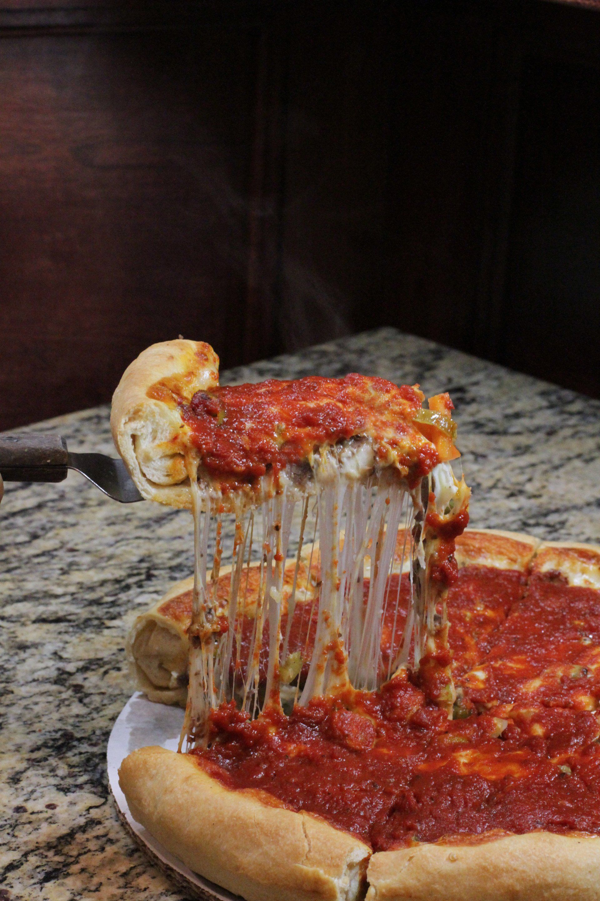 A pizza with a slice taken out of it on a table.
