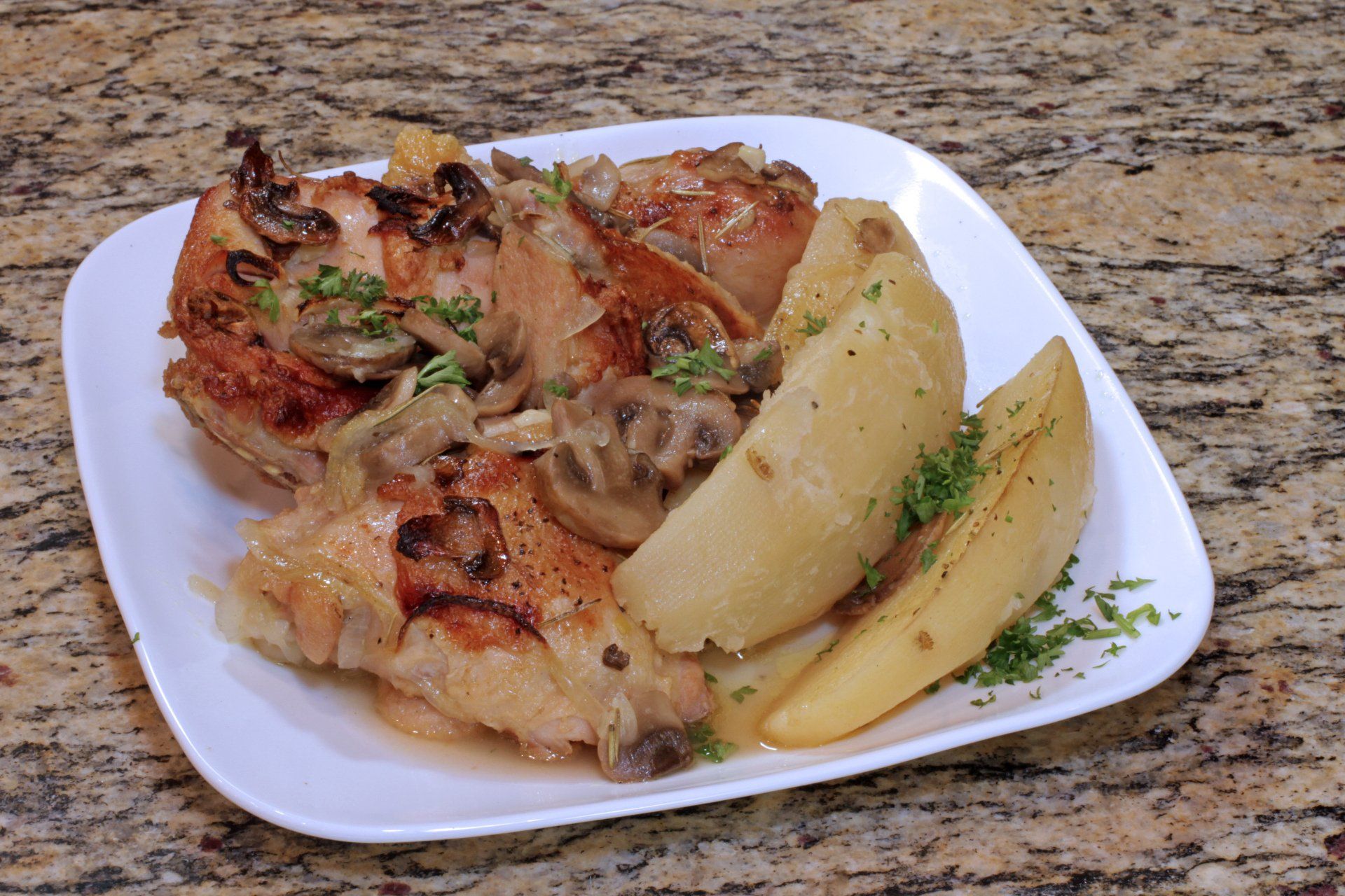 A white plate topped with chicken potatoes and mushrooms