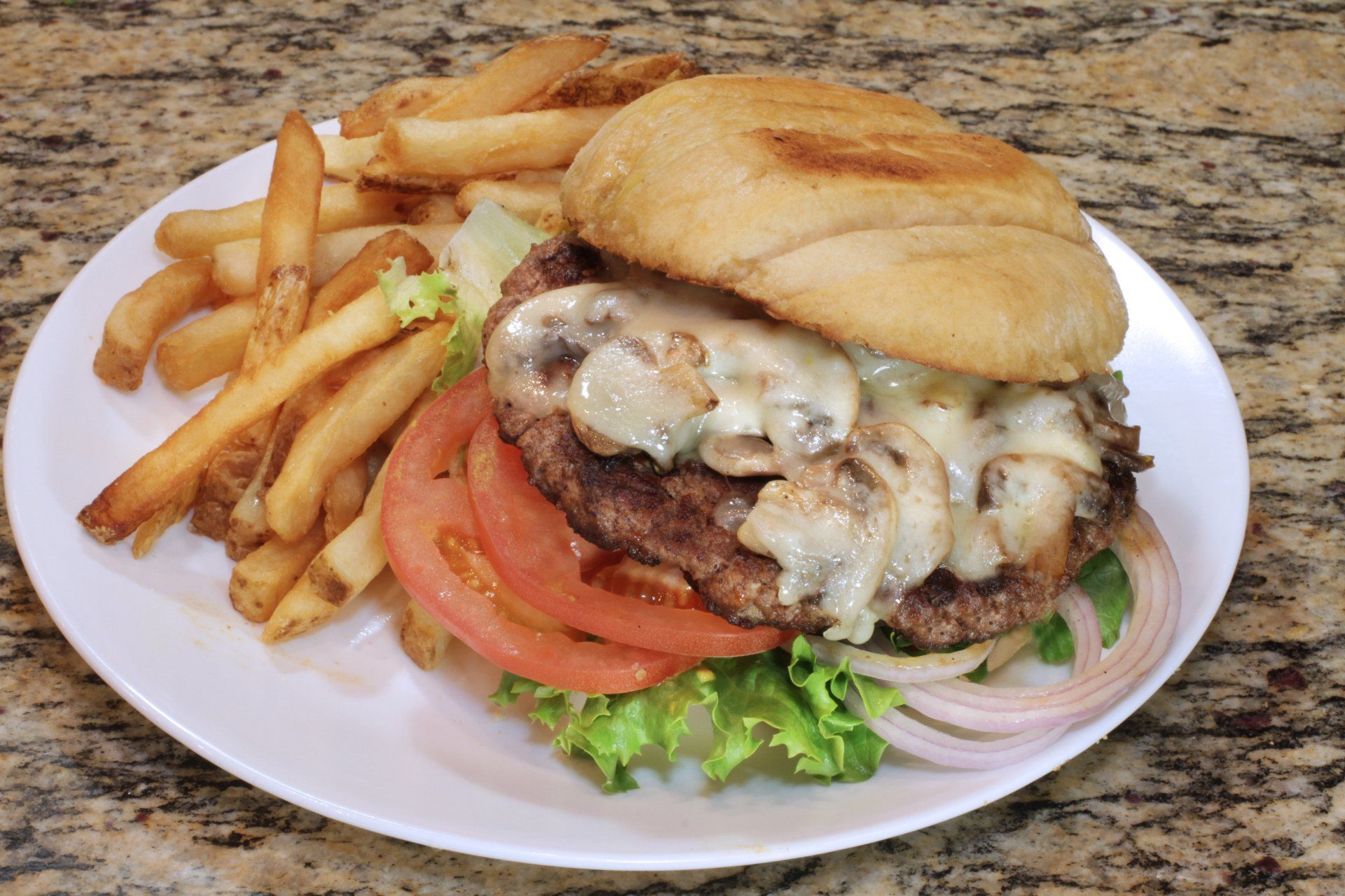 A white plate topped with a hamburger and french fries.