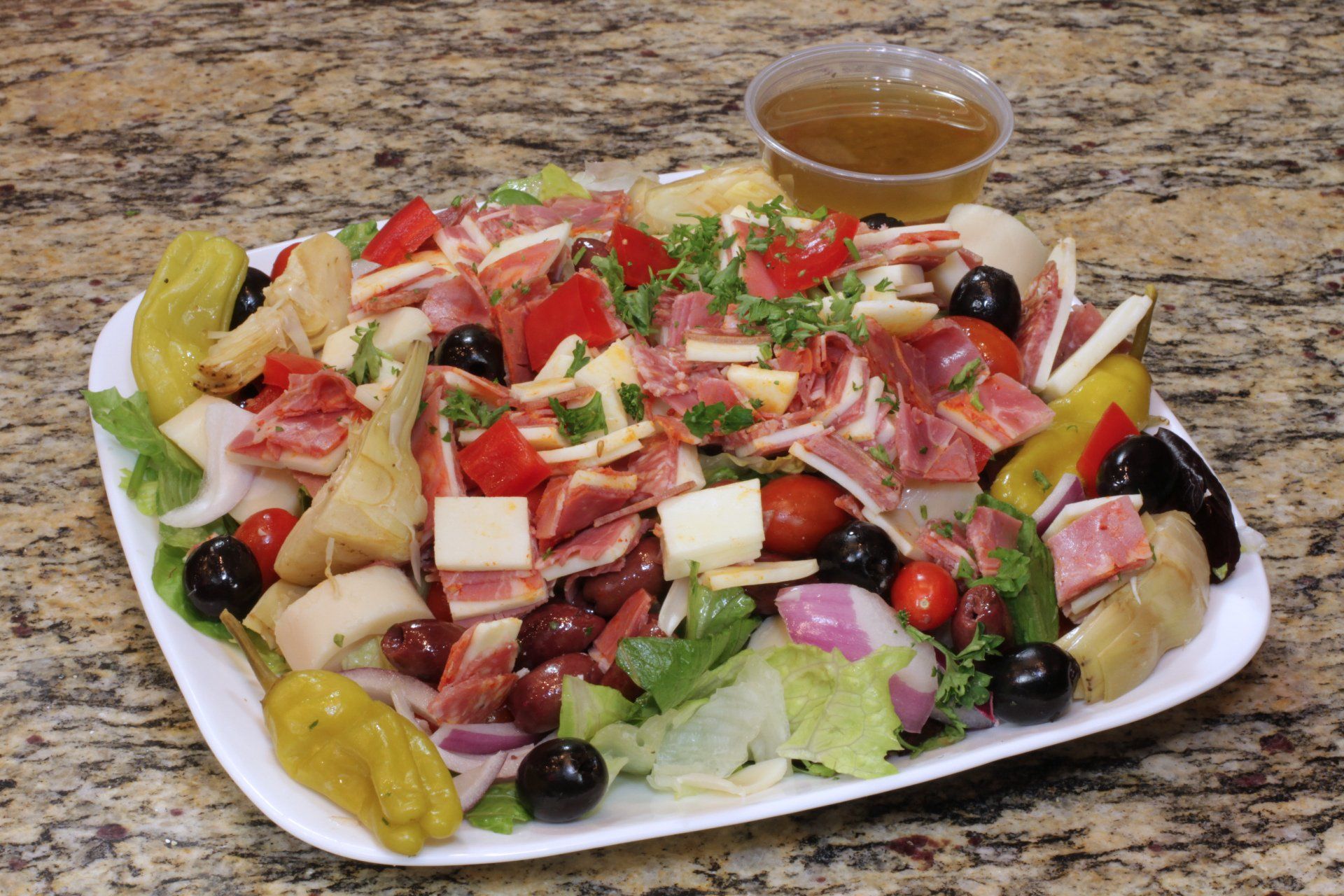 A white plate topped with a salad and a cup of dressing.