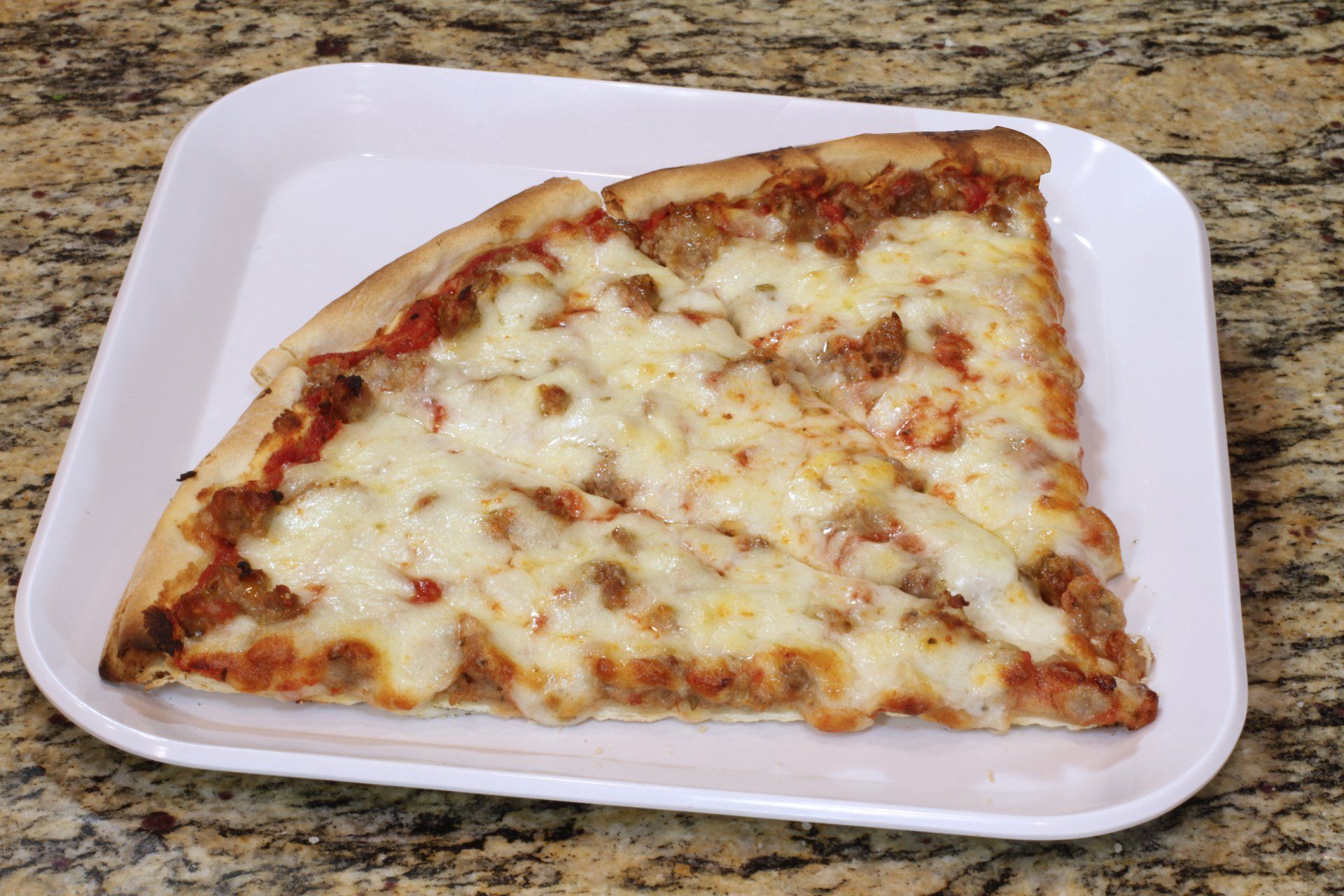 A slice of pizza is on a styrofoam tray on a counter.