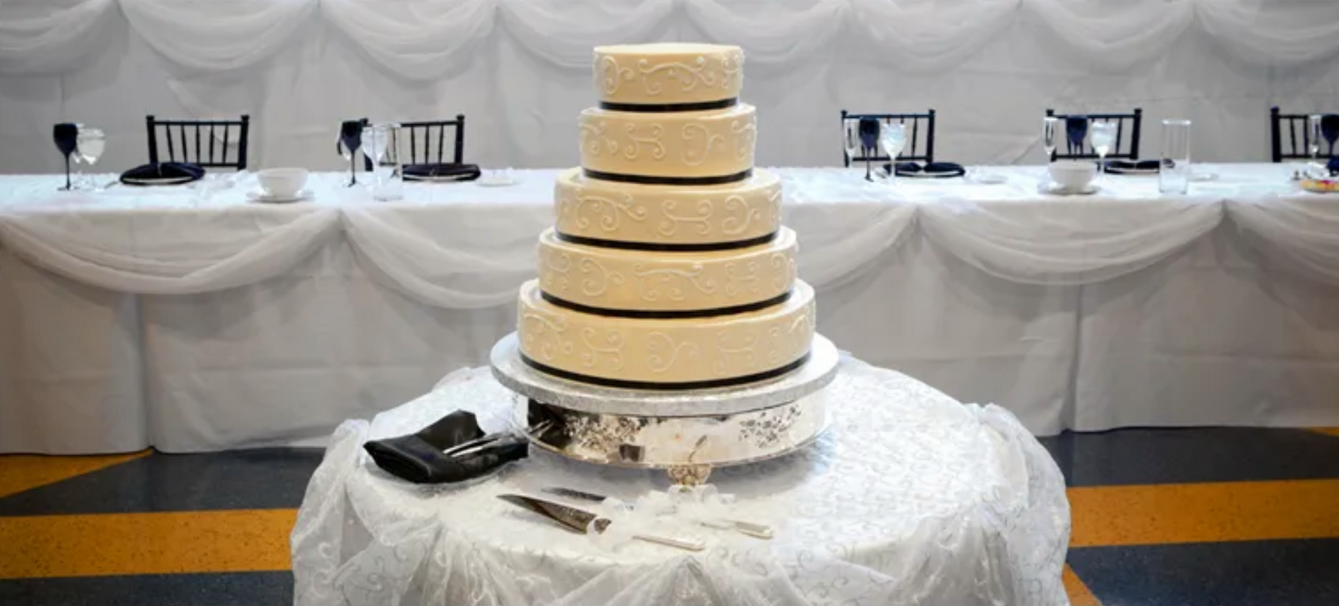 A wedding cake is sitting on a table with a white table cloth.