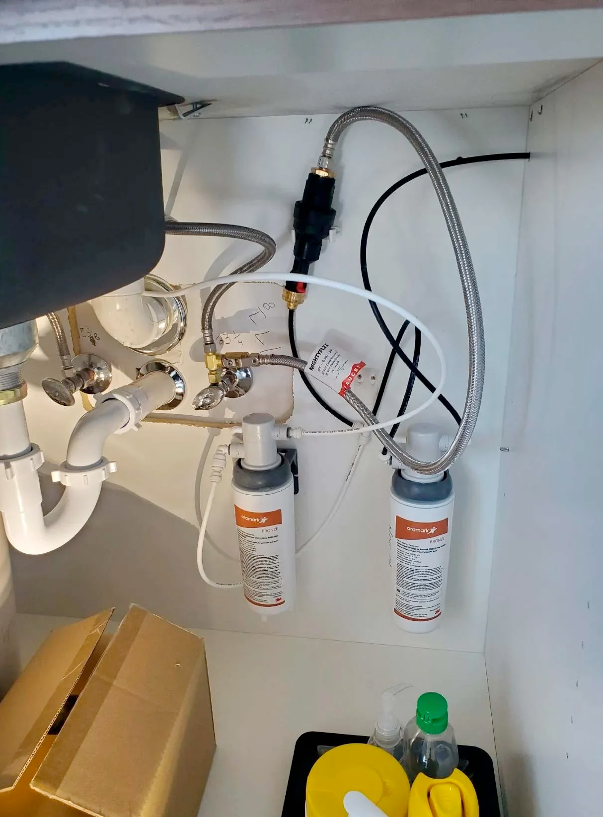 A kitchen sink with a water filter underneath it.