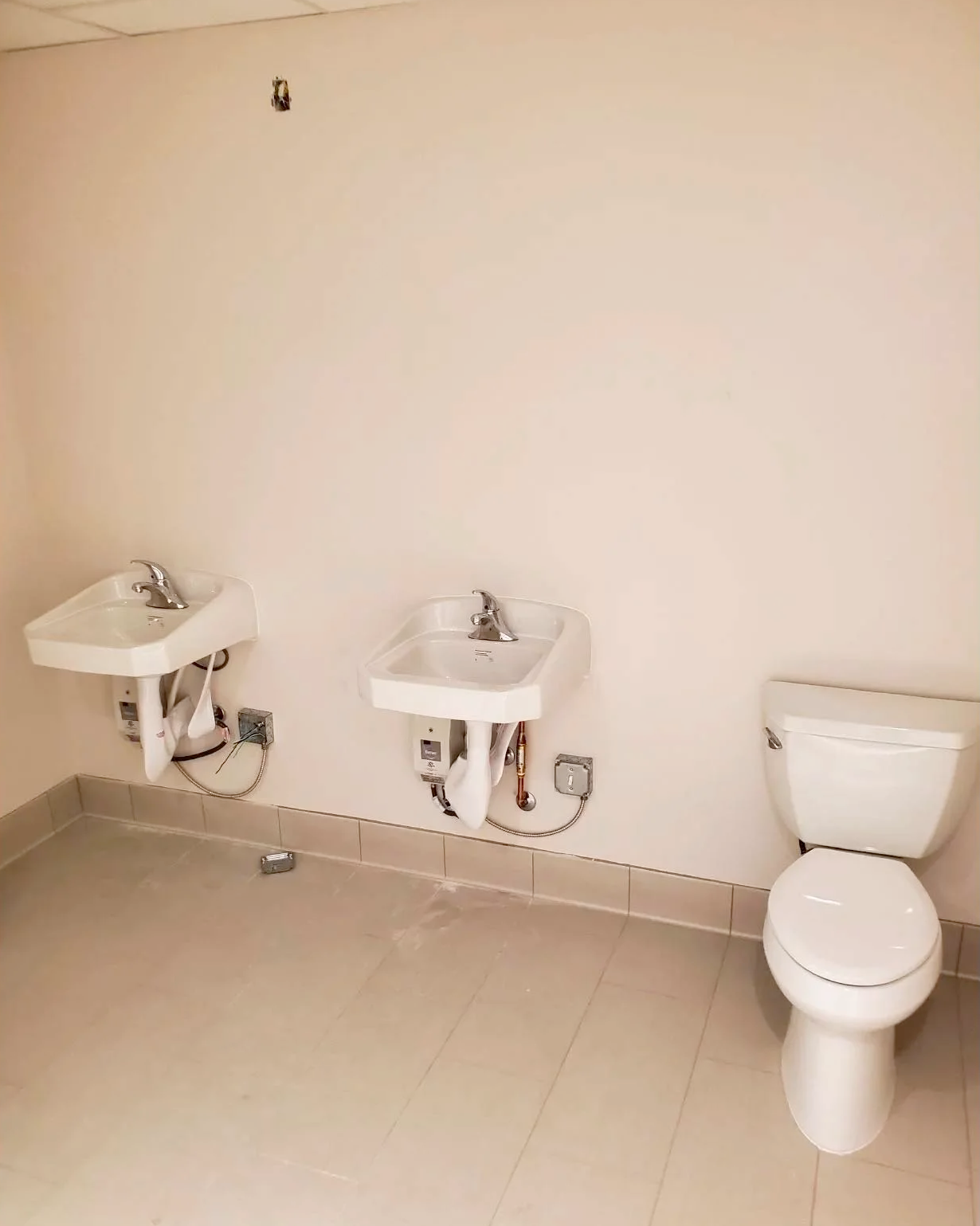 A bathroom with three sinks and a toilet