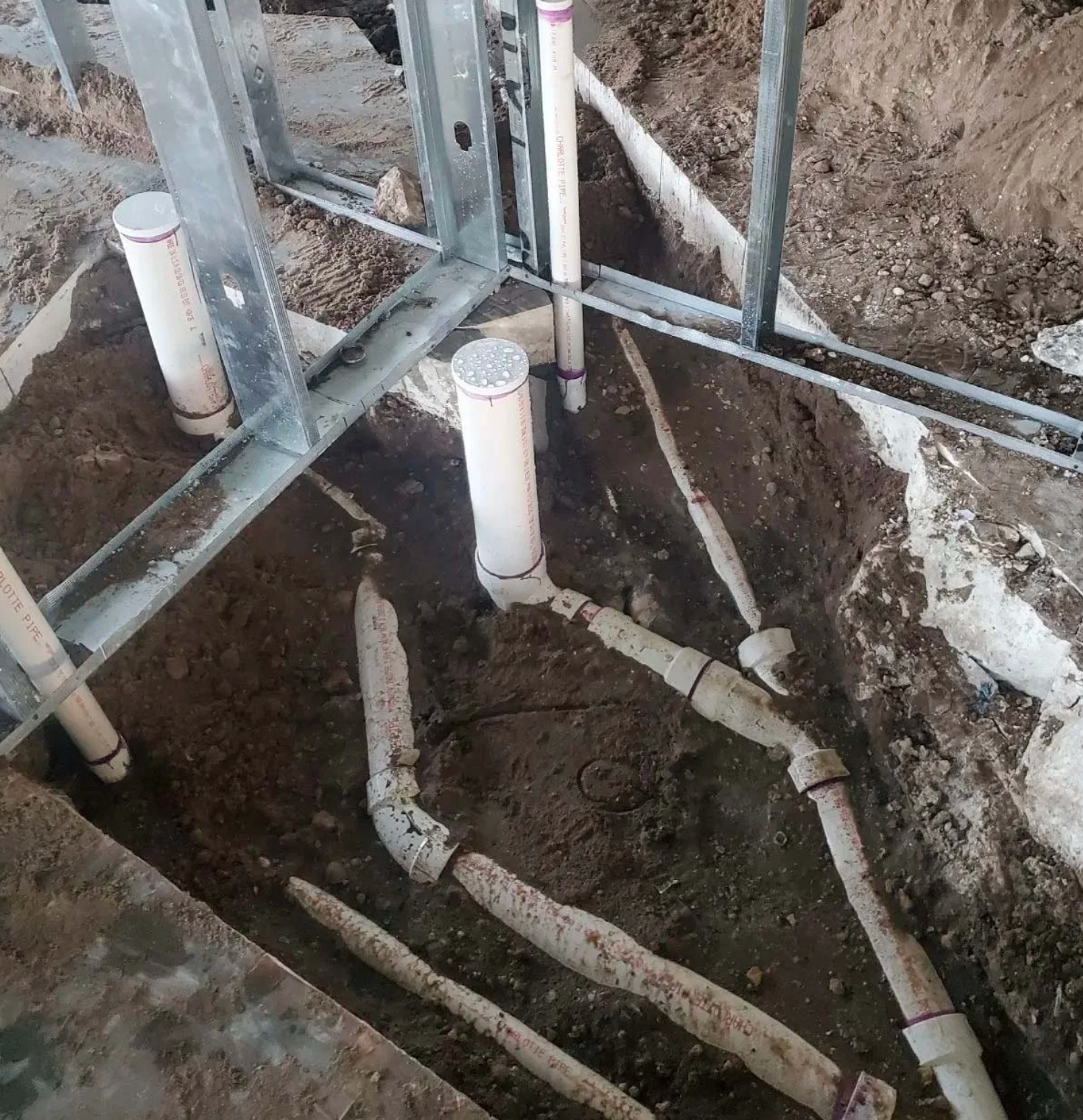 A bunch of pipes are laying in the dirt.