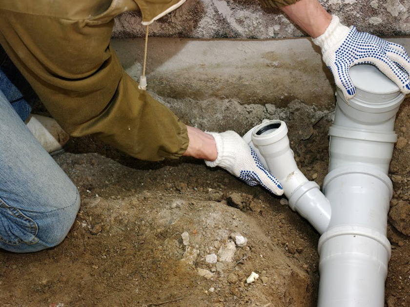 A man is installing a drain pipe in the ground.