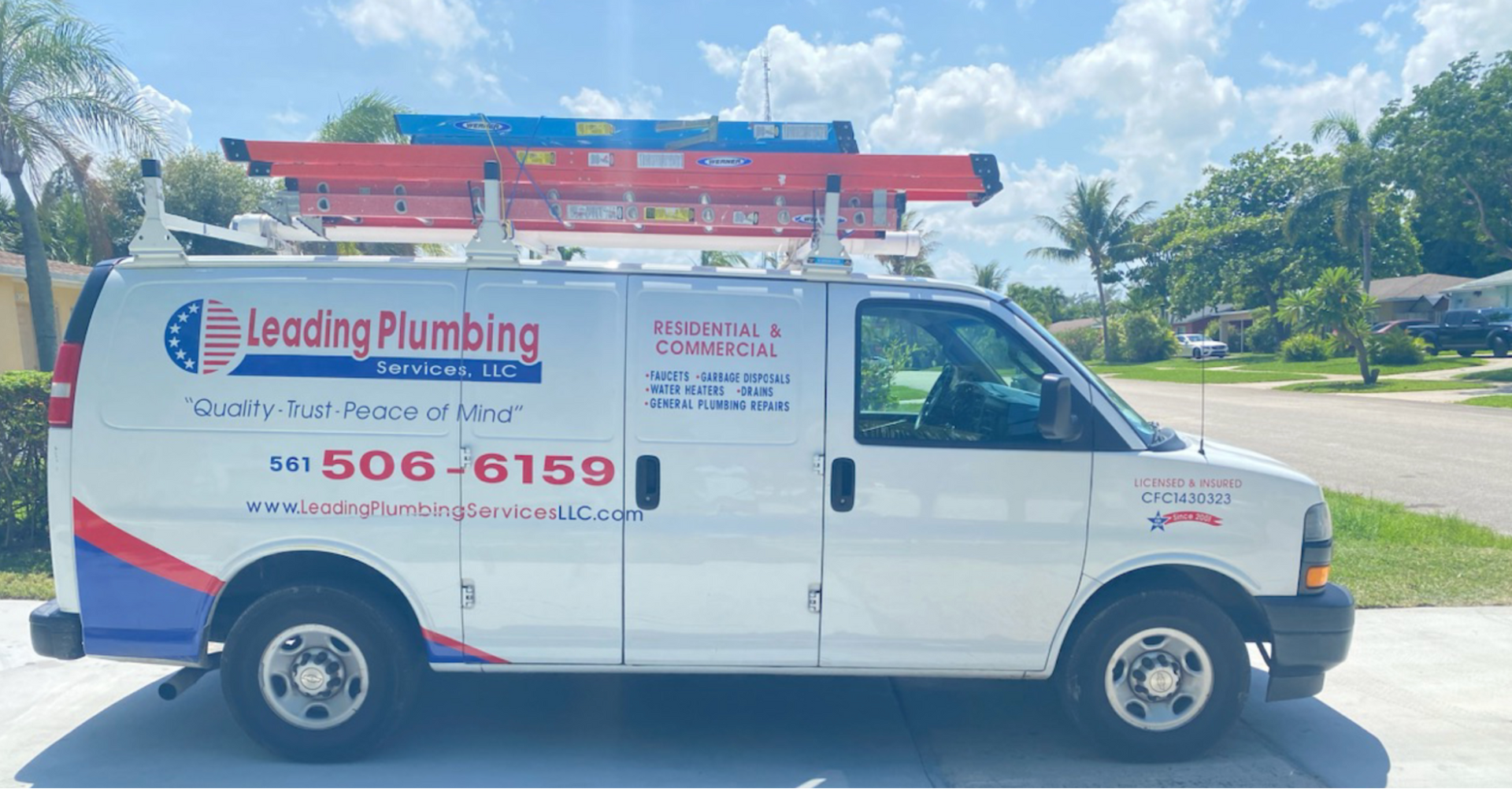 A leading plumbing van is parked in a driveway.