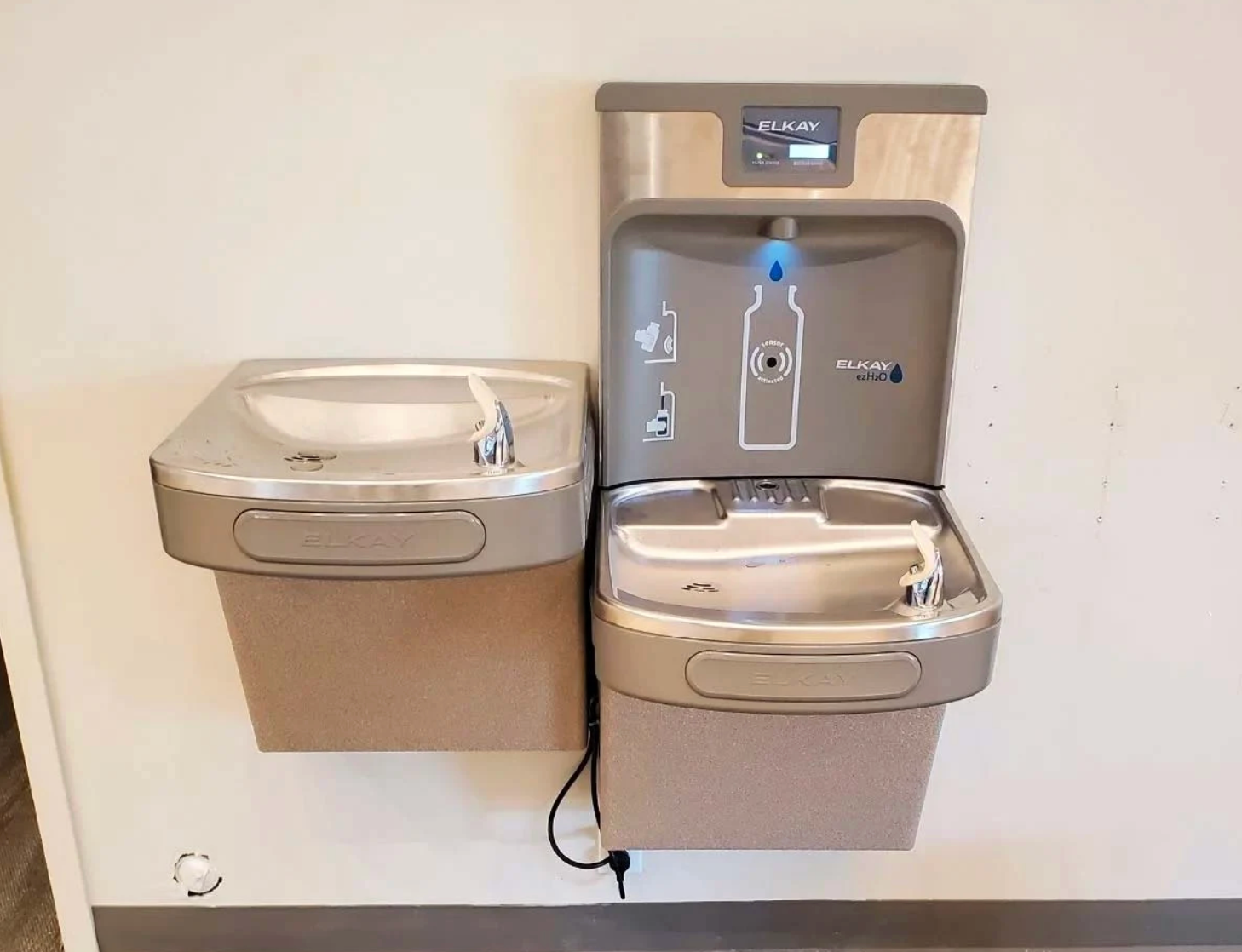 Two water fountains are hanging on a wall next to each other.