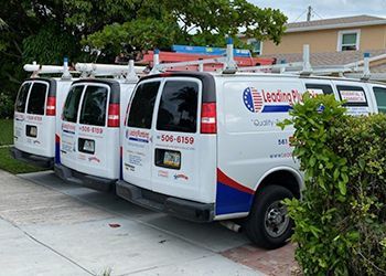 Three leading plumbing vans are parked on the side of the road.