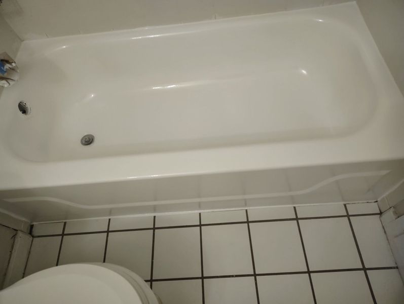 White bathtub with debris inside; tiled floor, white walls.