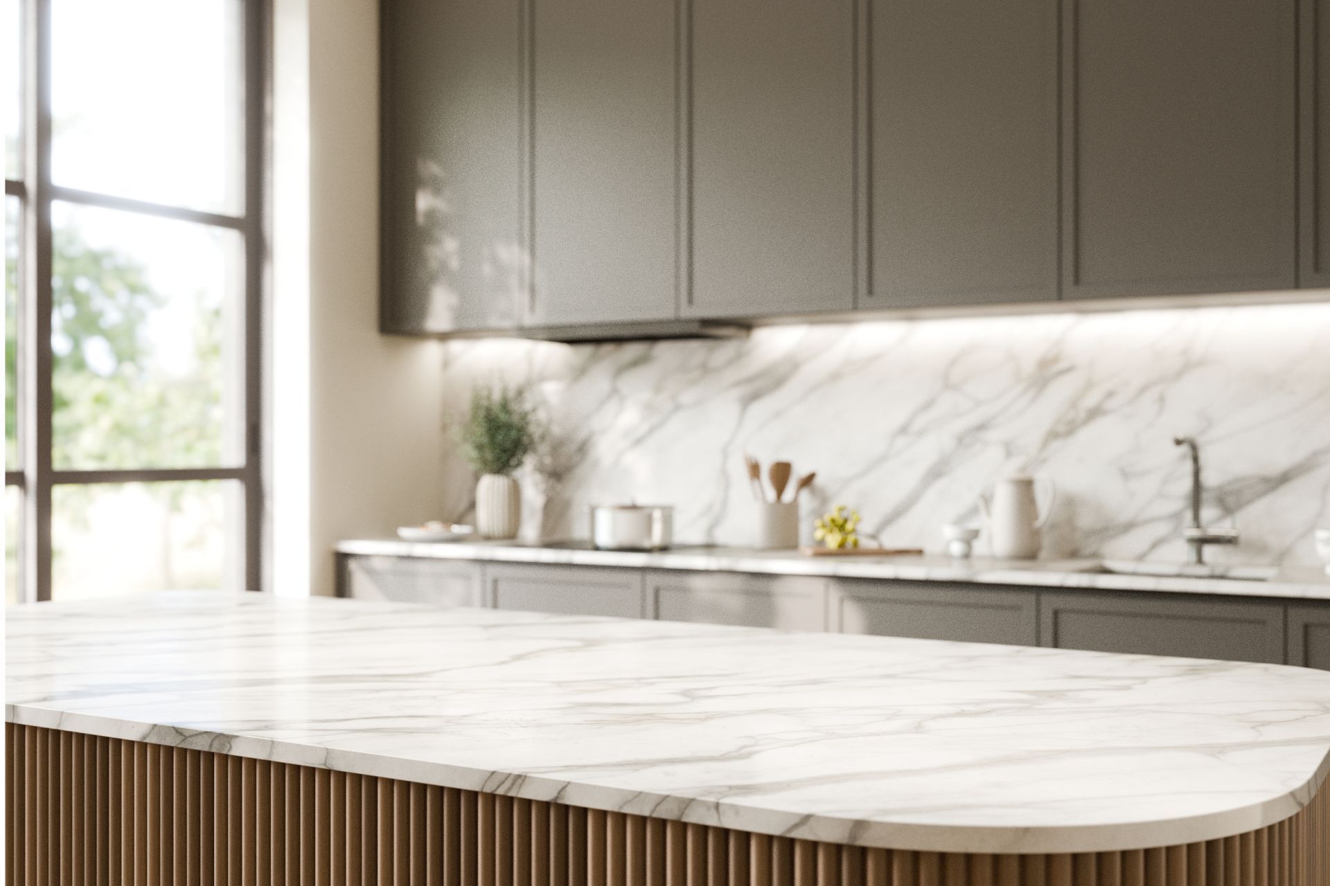 Modern kitchen with marble countertop, gray cabinets, and a window in the background.