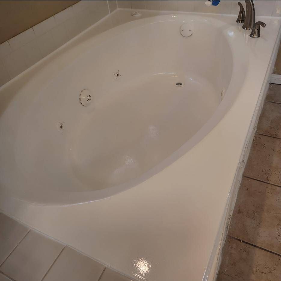 An oval, white jetted bathtub with metallic fixtures, set into a tiled bathroom floor.