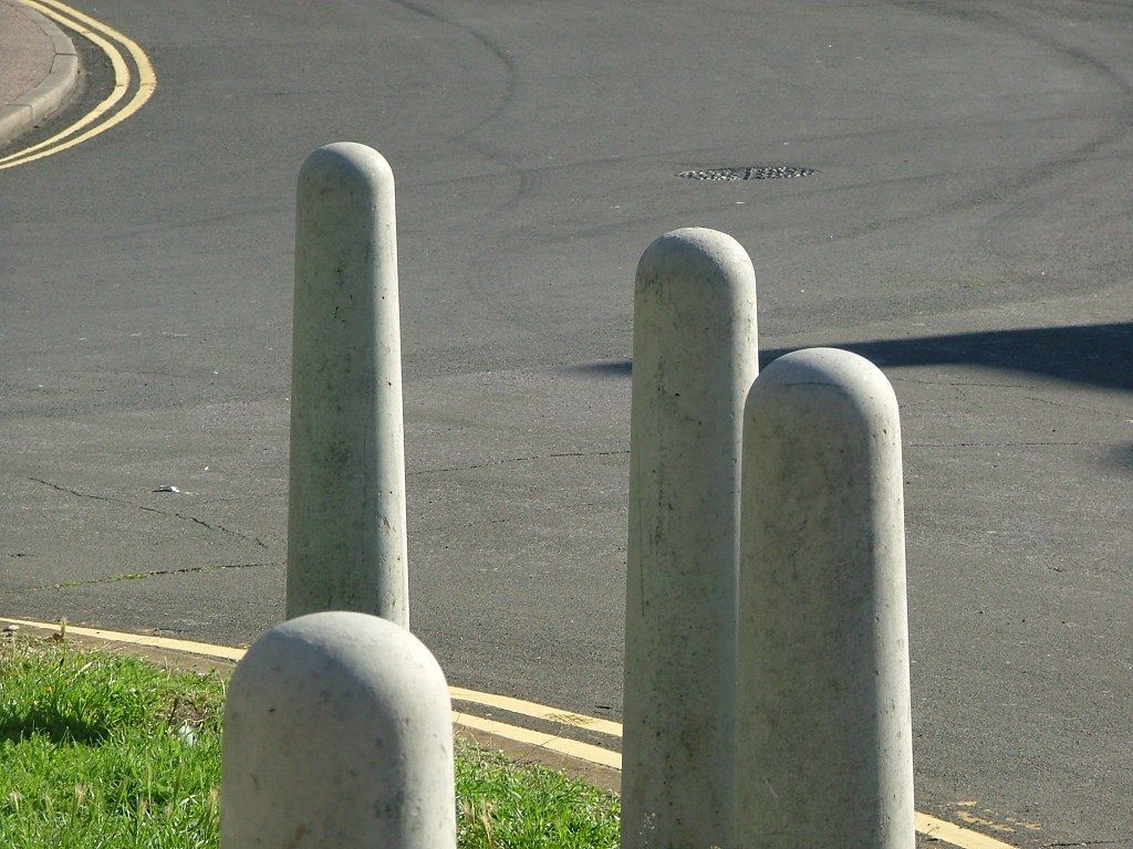 Three concrete poles on the side of a road