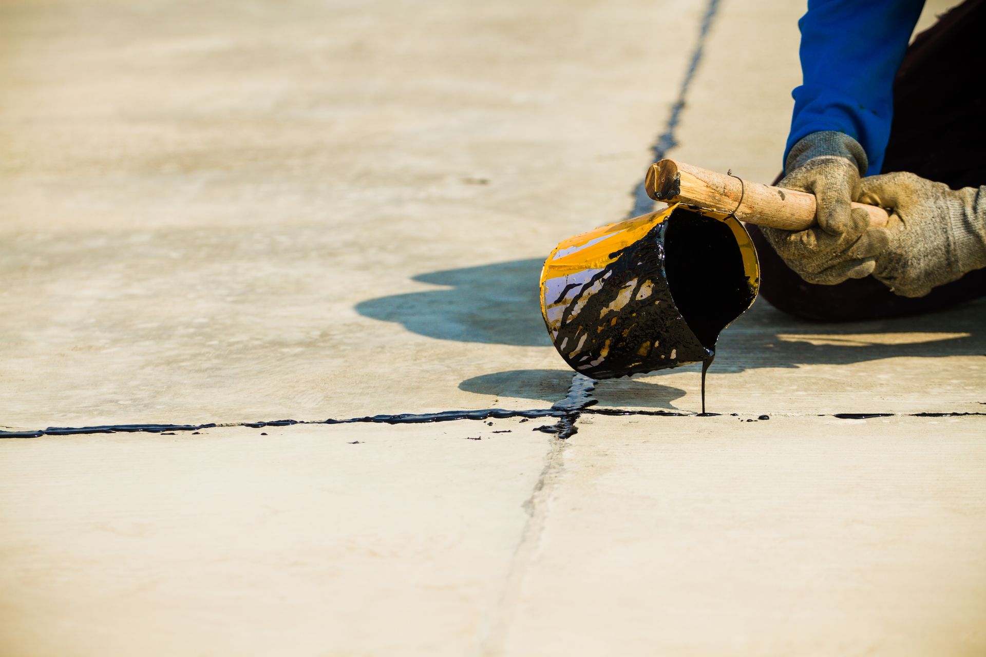 A person is pouring black paint on a concrete surface.
