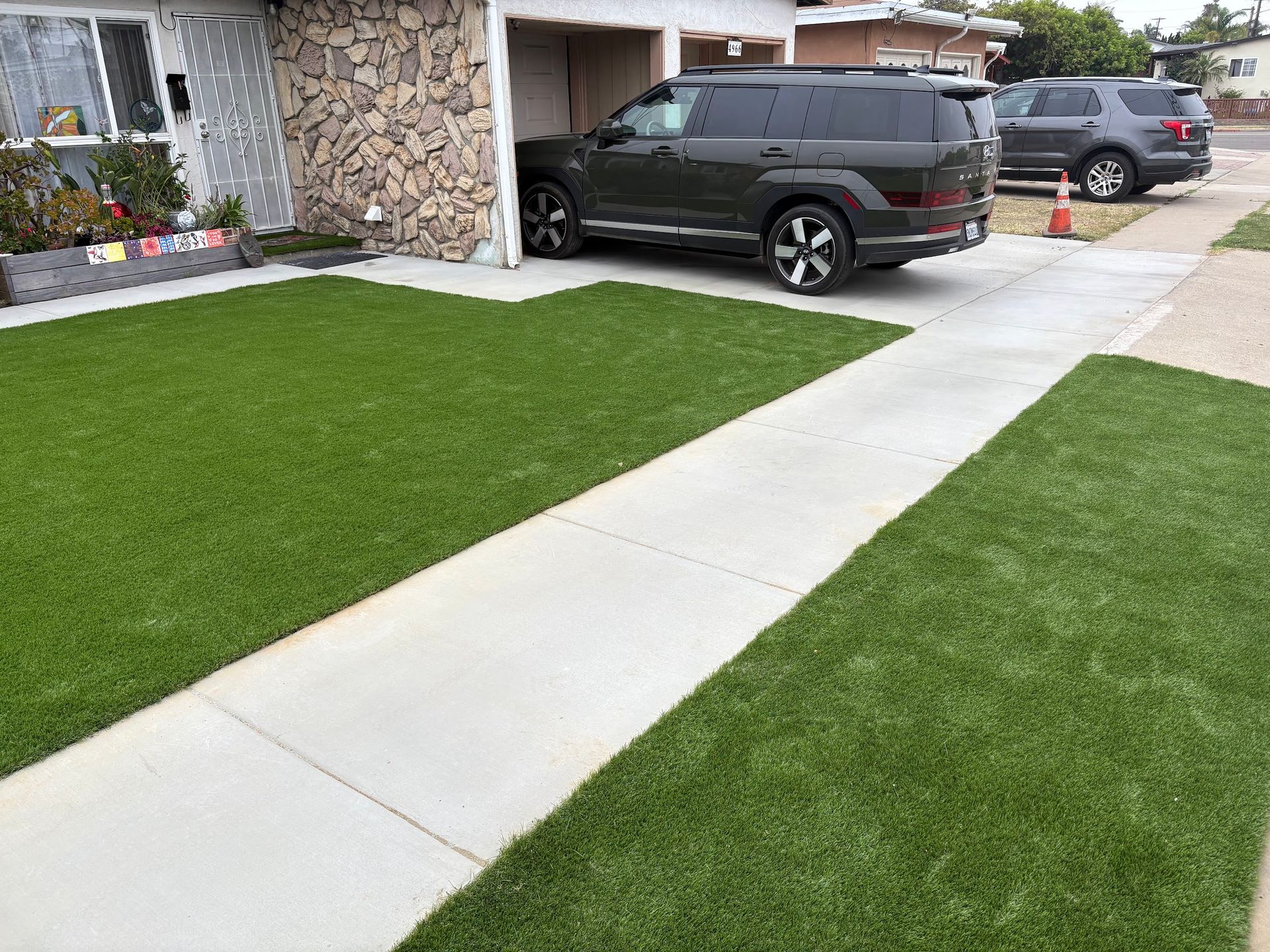 A concrete walkway in a park surrounded by grass and rocks.