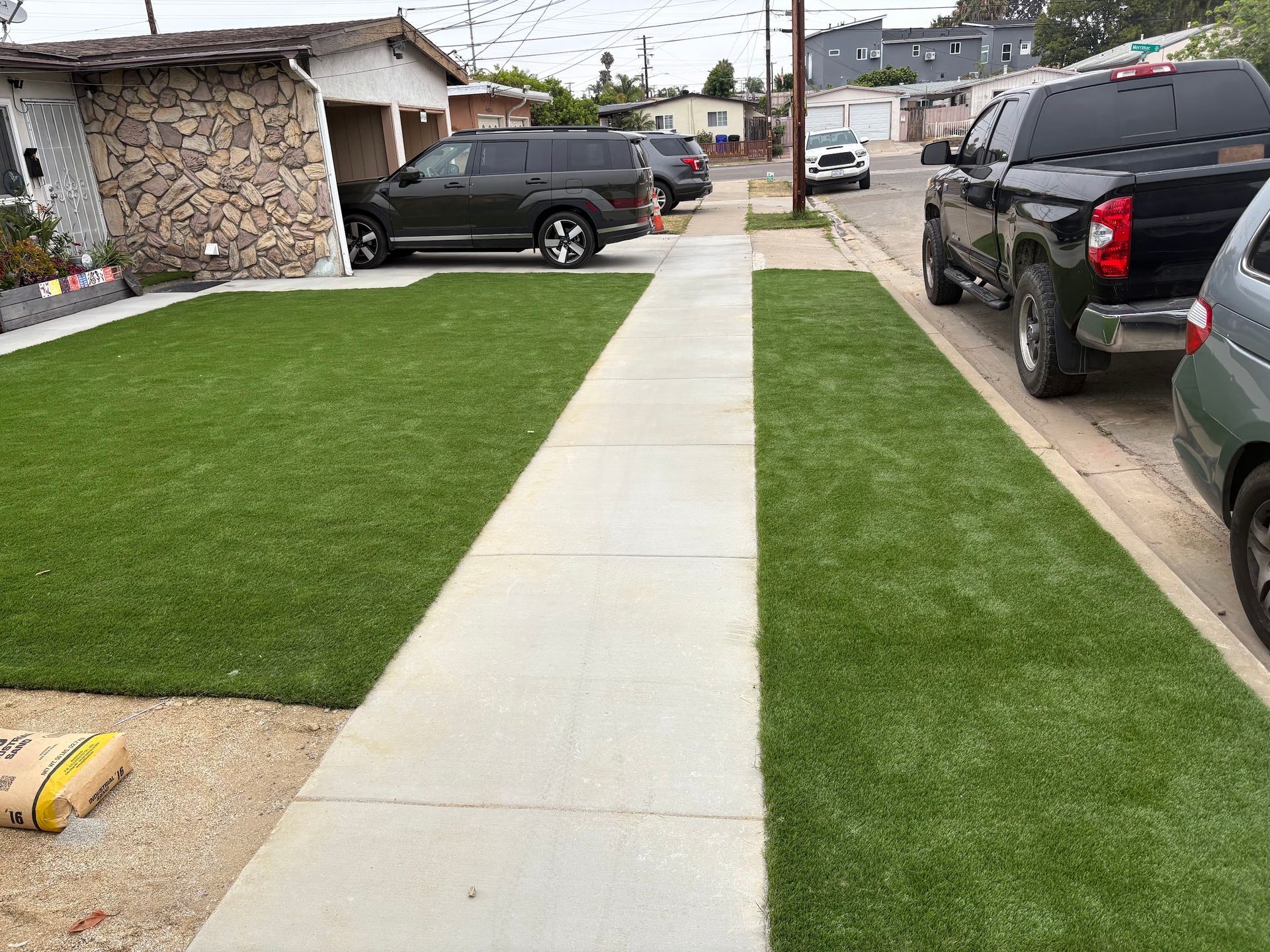 New concrete sidewalk with artificial grass in a San Diego neighborhood.