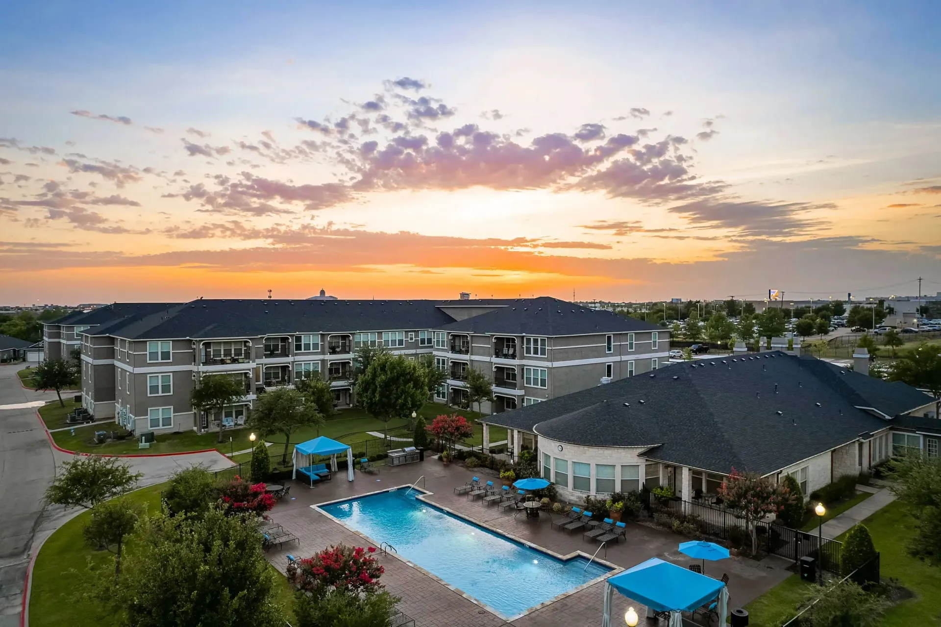 Apartment complex with pool and lounge area during sunset.