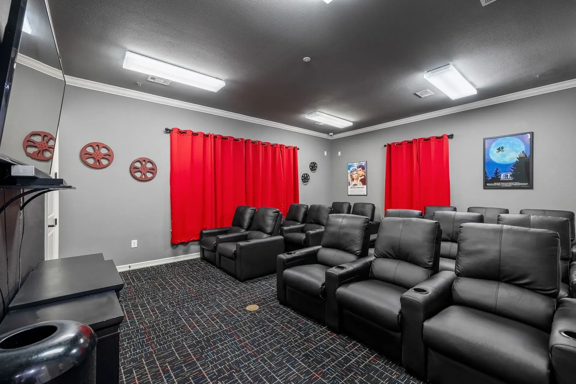 Theater room with black leather recliners and red curtains.