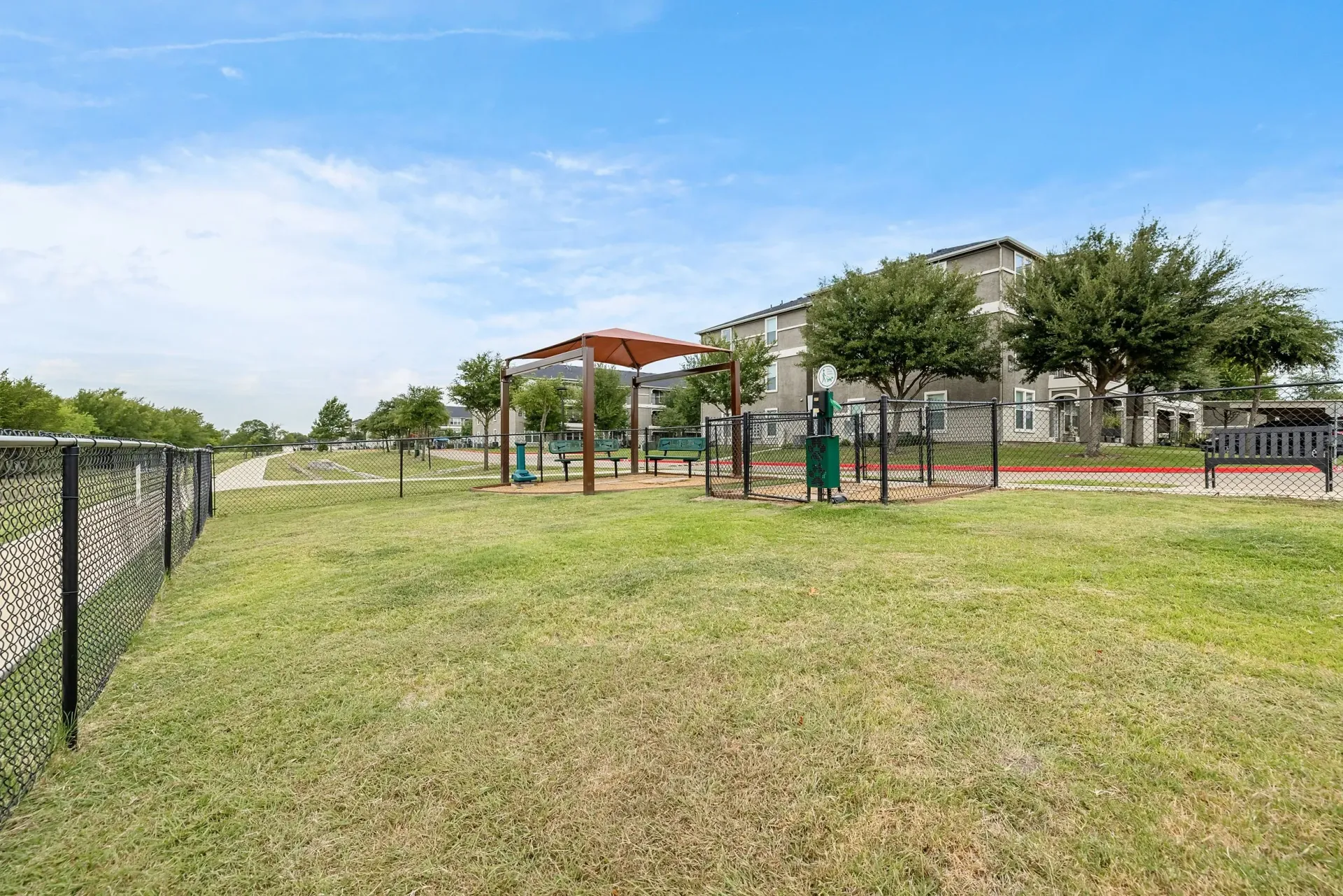 Enclosed dog park area with benches and waste station.