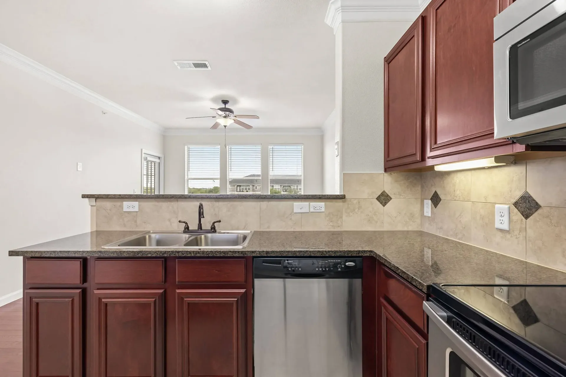 Modern kitchen with dark wood cabinets, granite countertops, stainless steel appliances, and a breakfast bar.