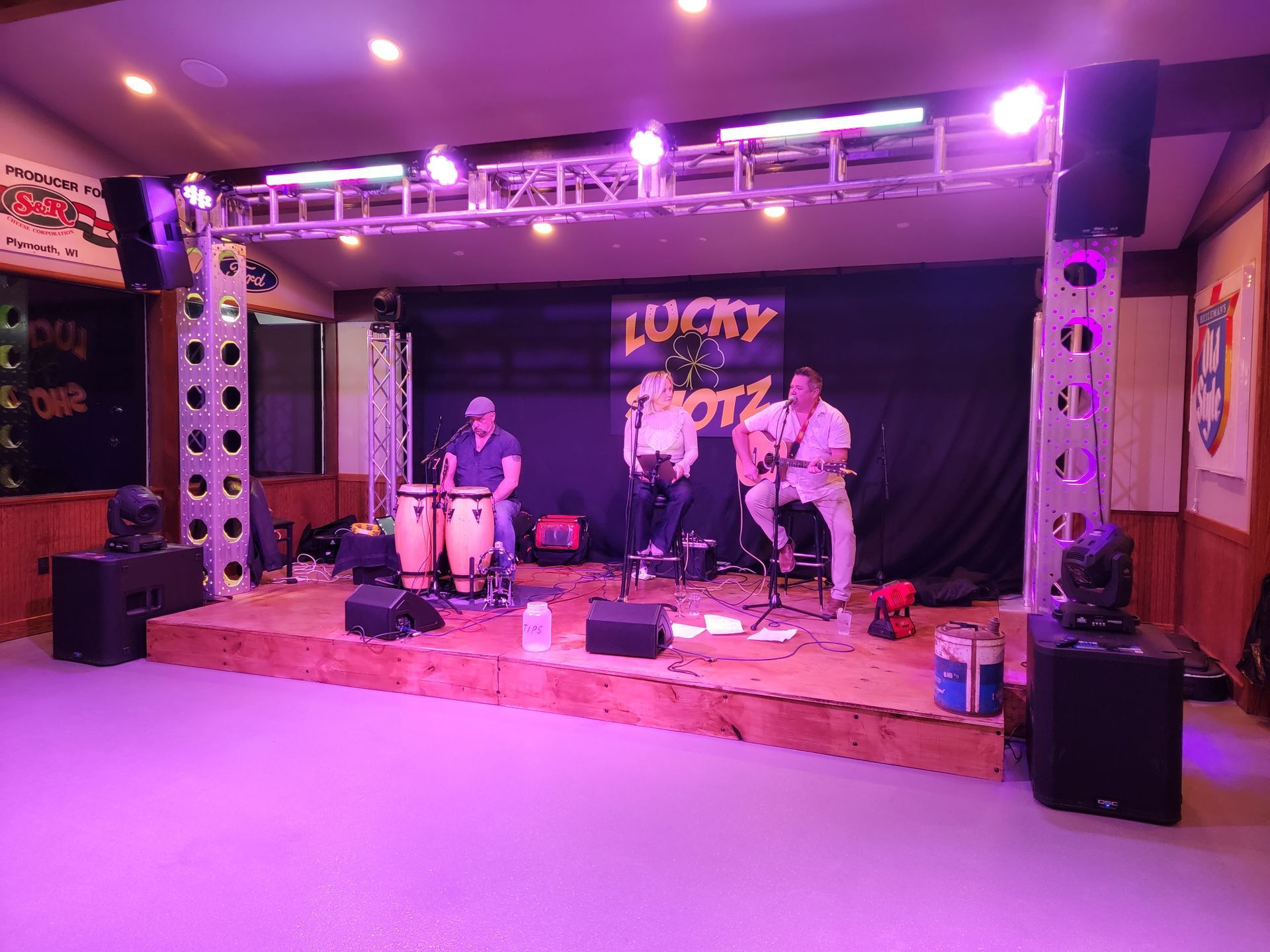 A group of people are playing instruments on a stage with purple lights.