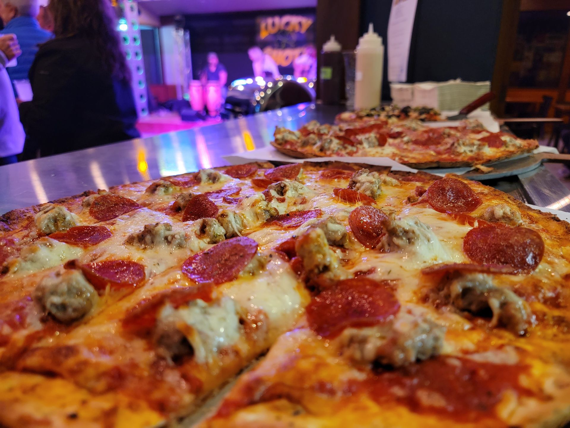 A pepperoni pizza is sitting on a table in a restaurant.